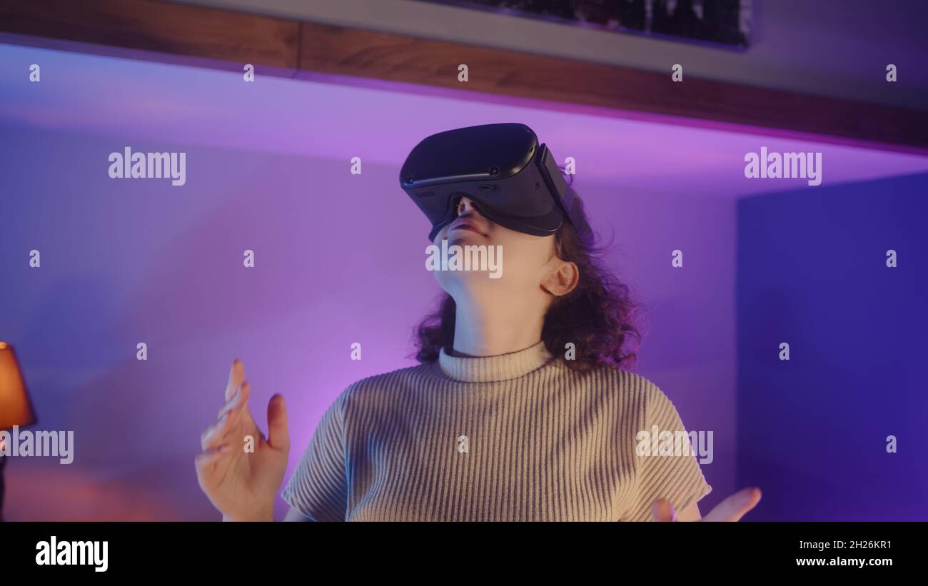 Curly haired girl using VR glasses standing at home. She explore the new  experiences with virtual reality Stock Photo - Alamy