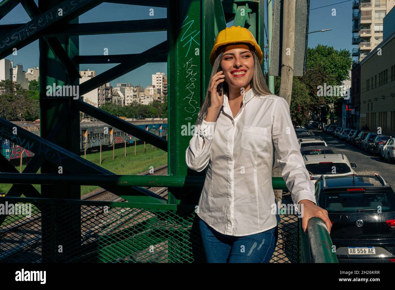 Beautiful young woman engineer or supervisor, wearing a safety helmet, talking on a cell phone while taking a short break inspecting a railroad pedest Stock Photo
