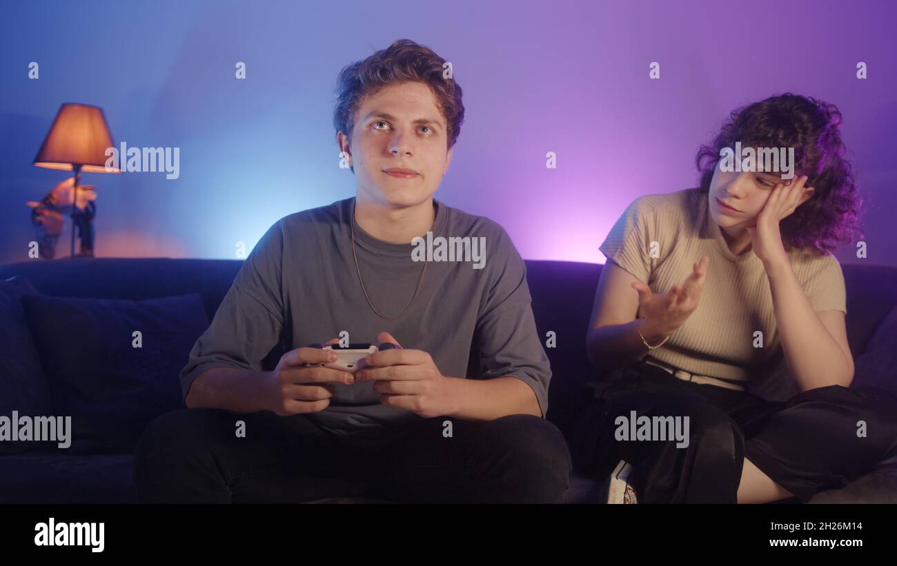 Young beautiful girl is offended to her careless boyfriend playing game