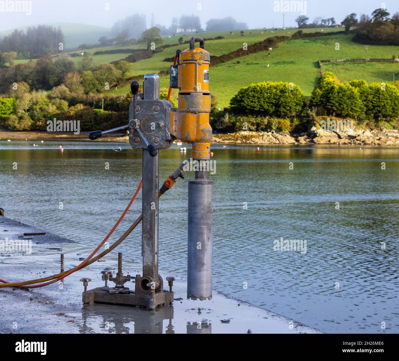 Diamond tipped core drill attached to stand bolted into concrete Stock