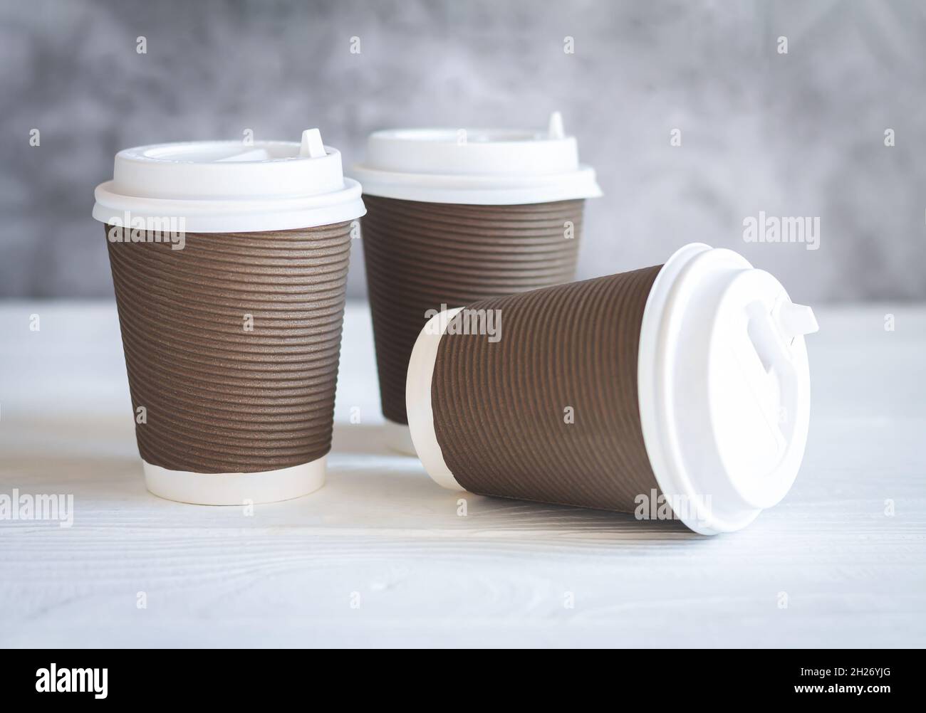 Three brown disposable paper coffee cup with white caps on wooden table.  Takeaway drink and eco-friendly tableware concept Stock Photo - Alamy, image size:1300x1002