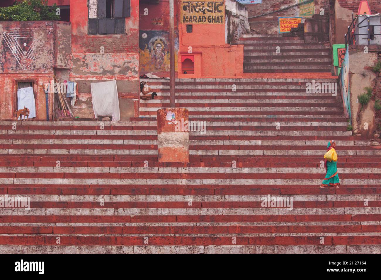 Varanasi, India– March 3, 2015: Unidentified woman making her  way shortly after dawn along the steps of Narad ghat above a Hindu bathing area Stock Photo