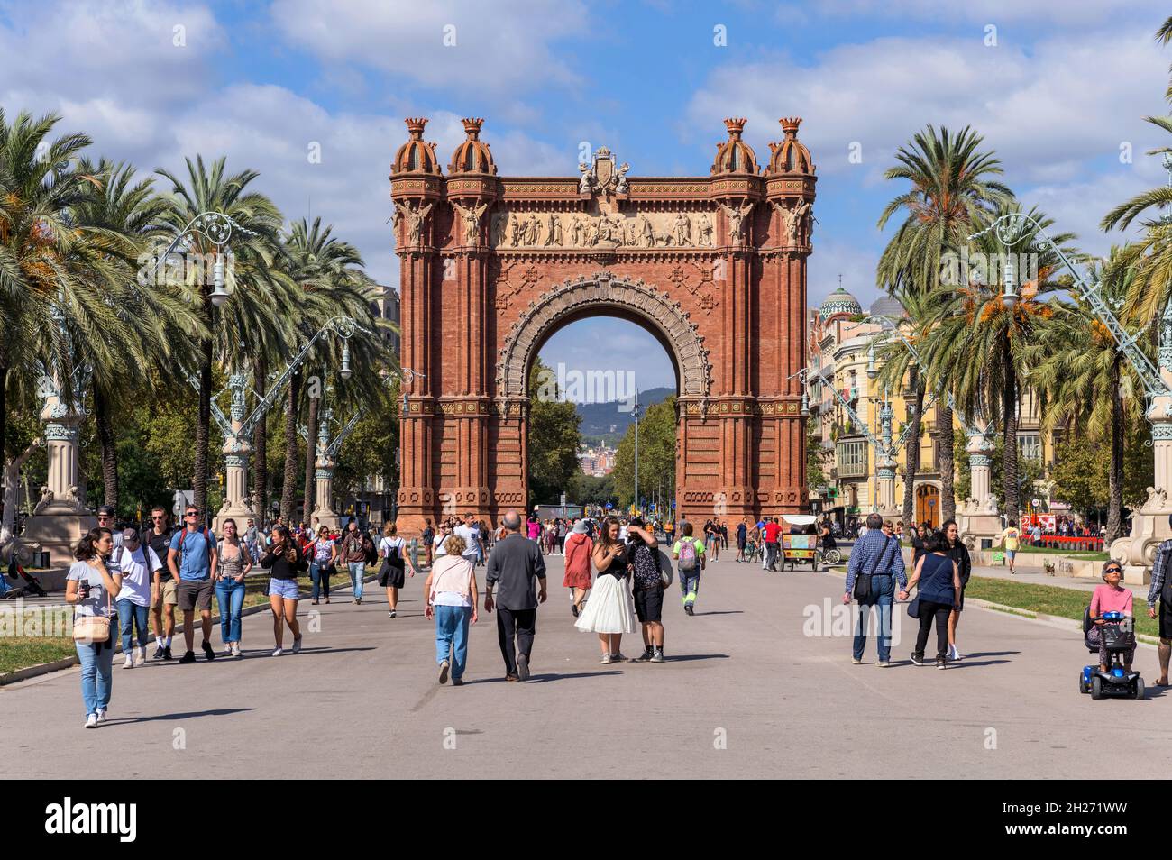 Arc de Triomf - Tourists are enjoying a sunny Autumn afternoon on broad promenade of Passeig de Lluís Companys at Arc de Triomf in Barcelona, Spain. Stock Photo