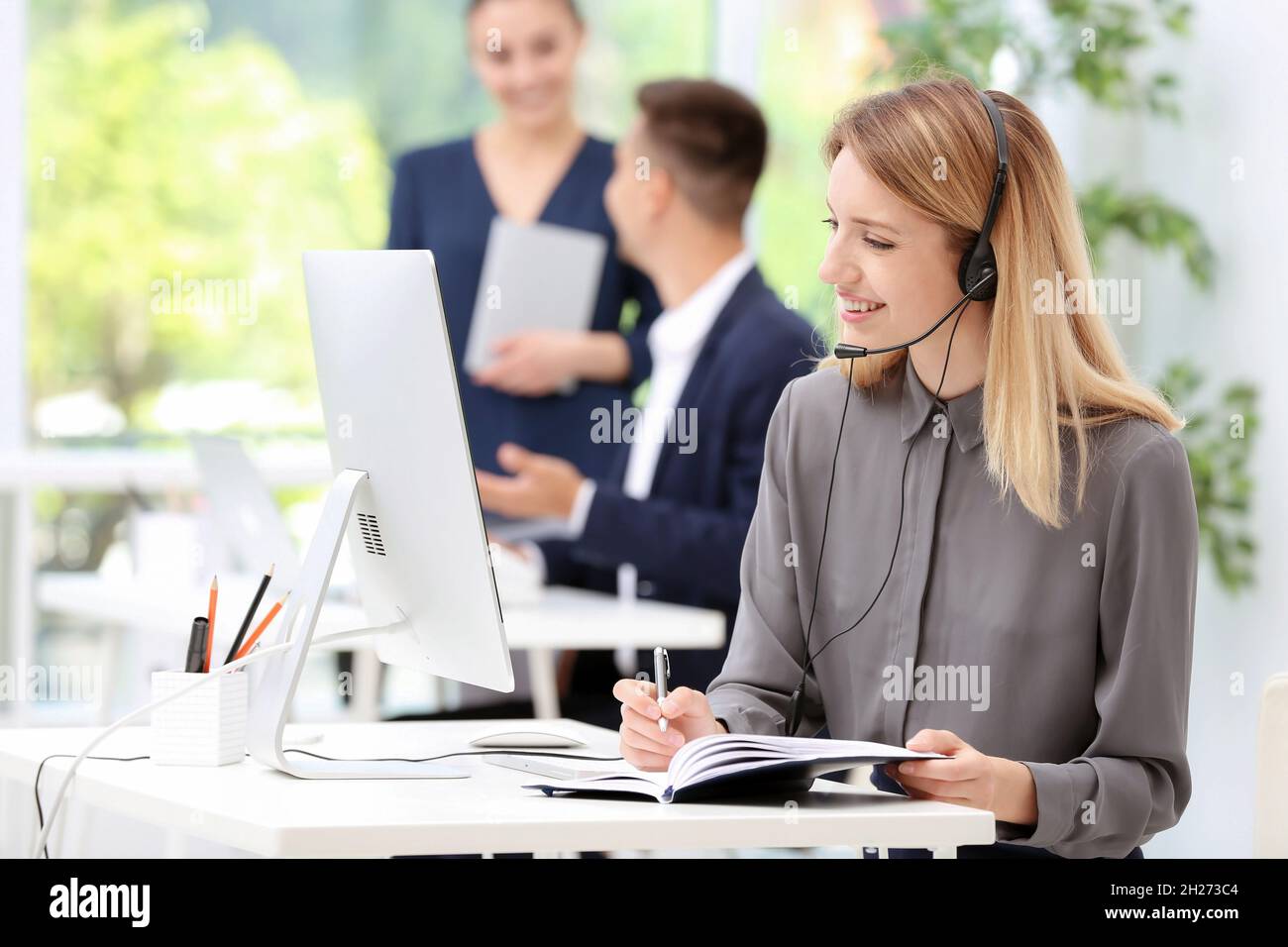 Female receptionist with headset at desk in office Stock Photo - Alamy