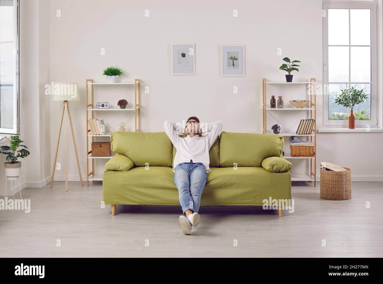 Happy relaxed young man sitting on comfortable couch in living room of his apartment Stock Photo