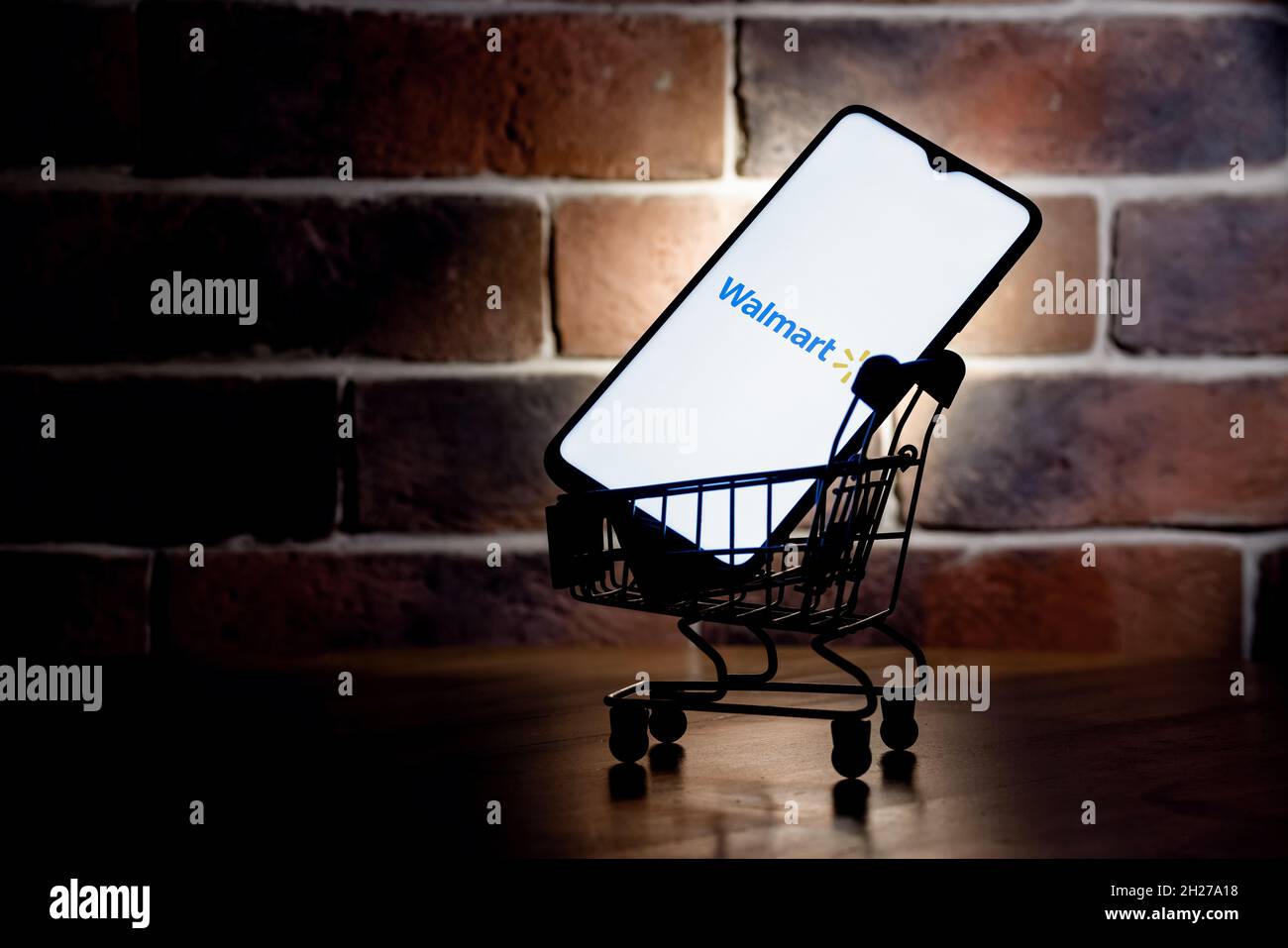 Walmart is an American multinational retail corporation. Smartphone with Walmart logo on screen in the shopping cart. Stock Photo