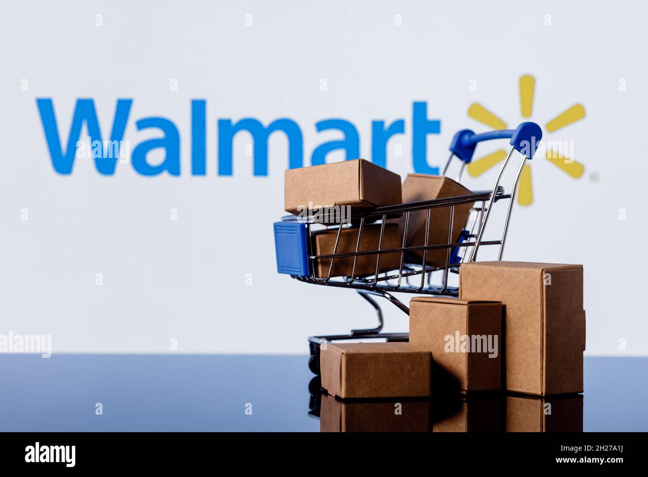 Walmart is an American multinational retail corporation. Shopping cart with parcels on the background of the Walmart logo. Stock Photo