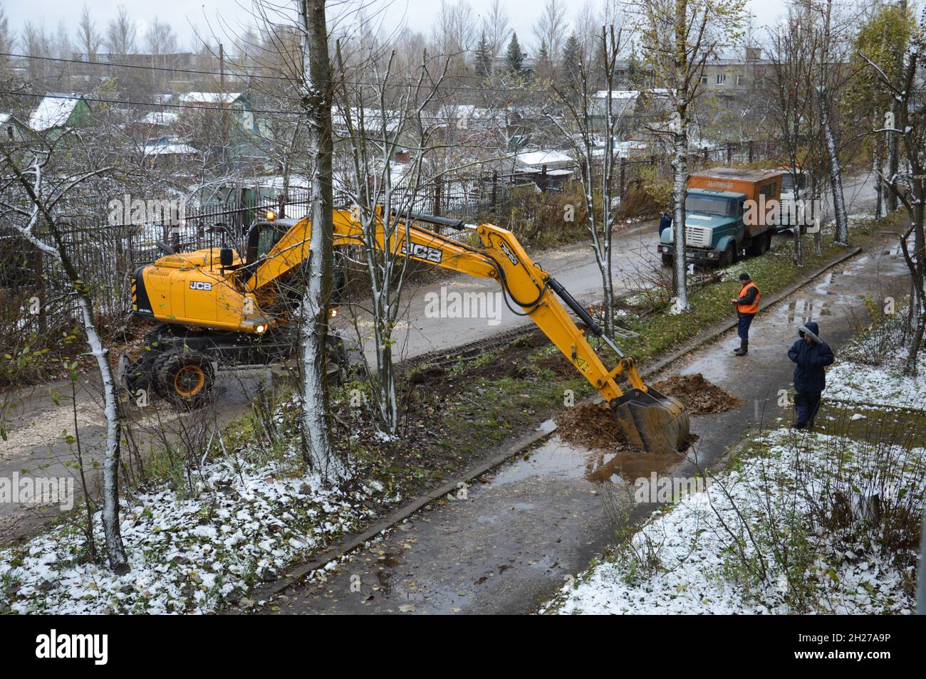 Kovrov, Russia. 1 November 2017. Utility workers discussing a troubleshooting plan on the pavement in front of a multistory residential house. Excavat Stock Photo