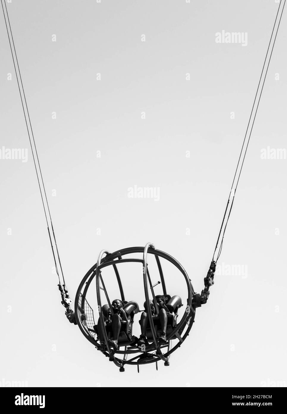 Minimalistic black and white image of couple on high wire swing at the funfair in Great Yarmouth Norfolk, UK. Stock Photo