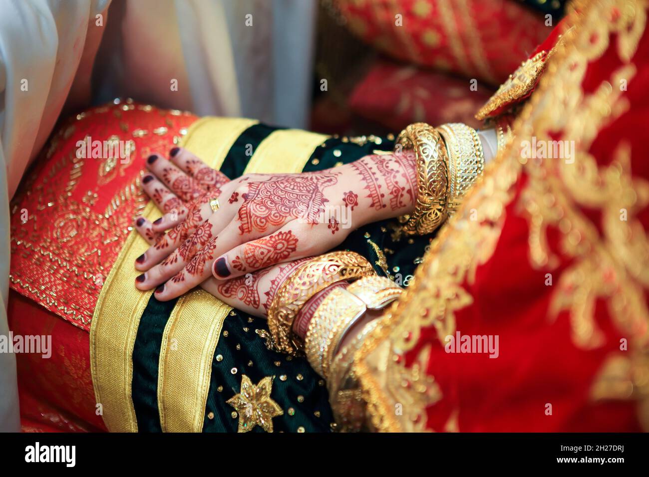 Close up hands and nails of Asian Muslim bride with henna paint tattoo and jewelry in a wedding ceremony. Traditional Minangkabau culture heritage. Stock Photo