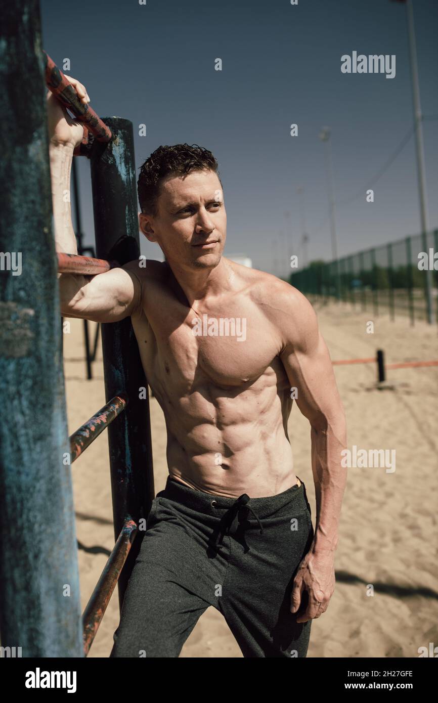 fitness, sport, training and lifestyle concept - young man with beautiful pumped up body posing on the beach Stock Photo