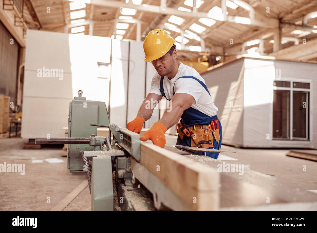 Handsome young man using woodworking machine in workshop Stock Photo
