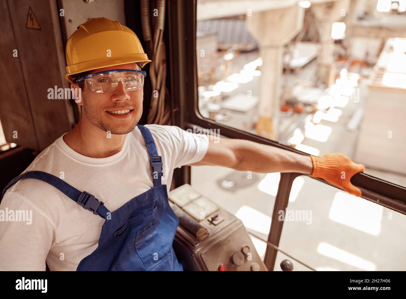 Cheerful man sitting in operator cabin of industrial crane Stock Photo