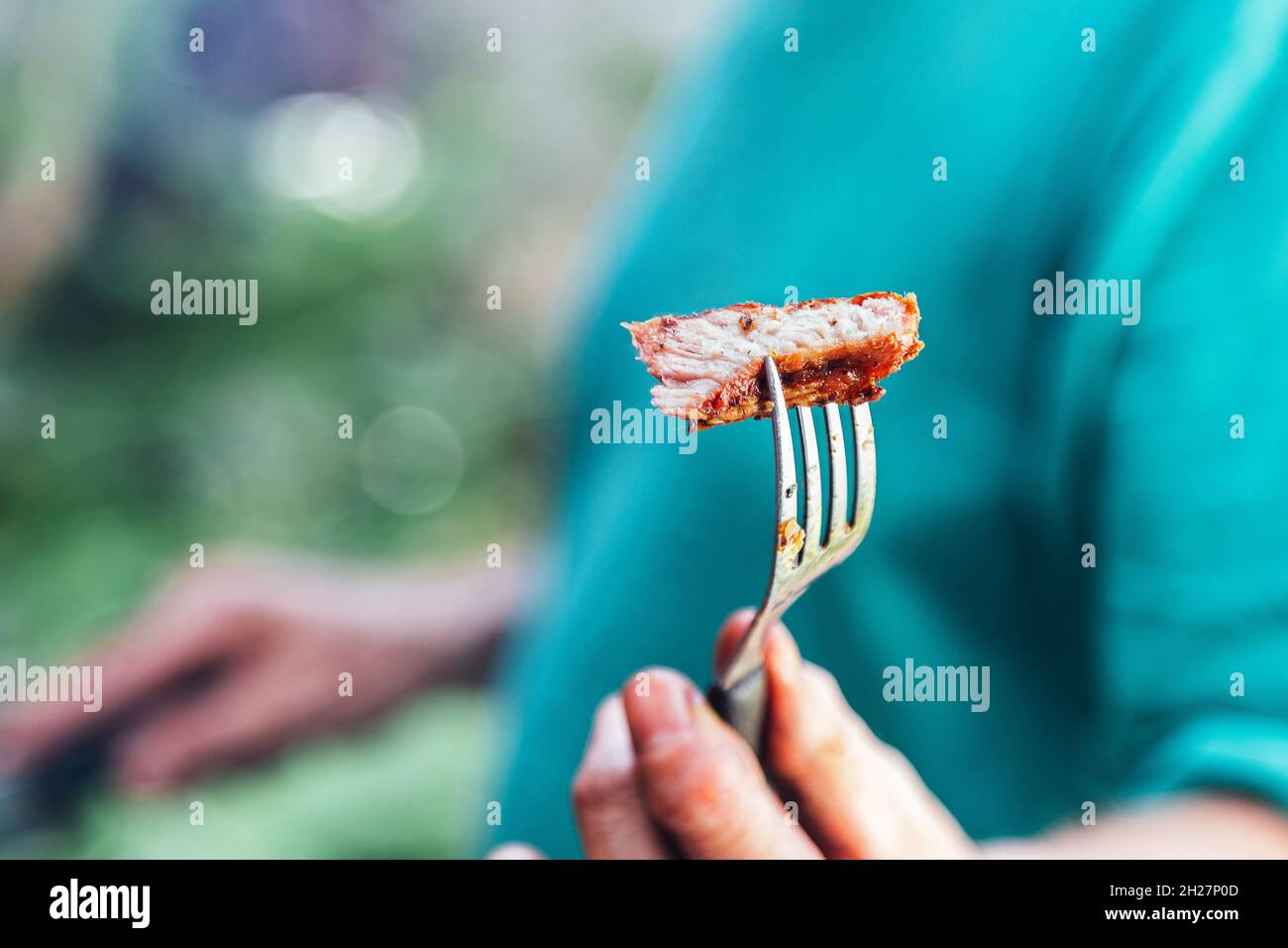 Man offering a piece of meat roasted with a fork. Stock Photo