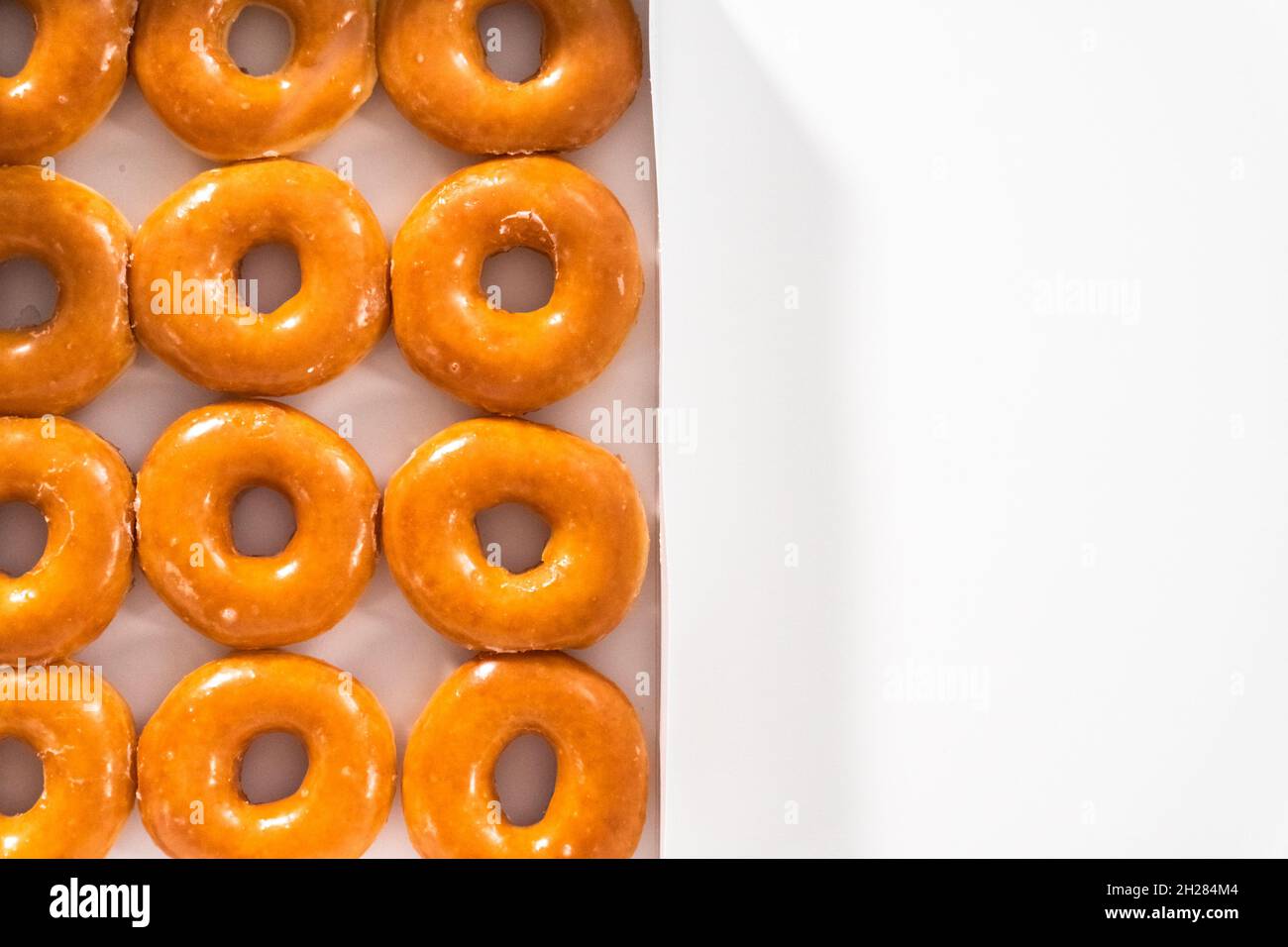 Flat lay. Plain glazed storebought doughnuts in a white paper box