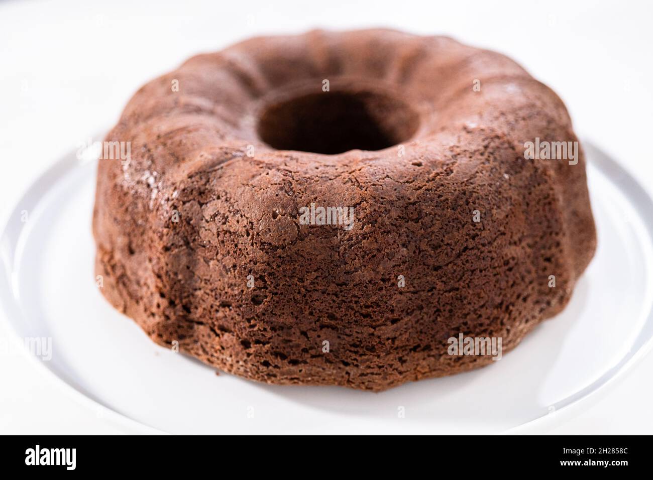 Freshly baked chocolate bundt cake on a white cake stand Stock Photo ...