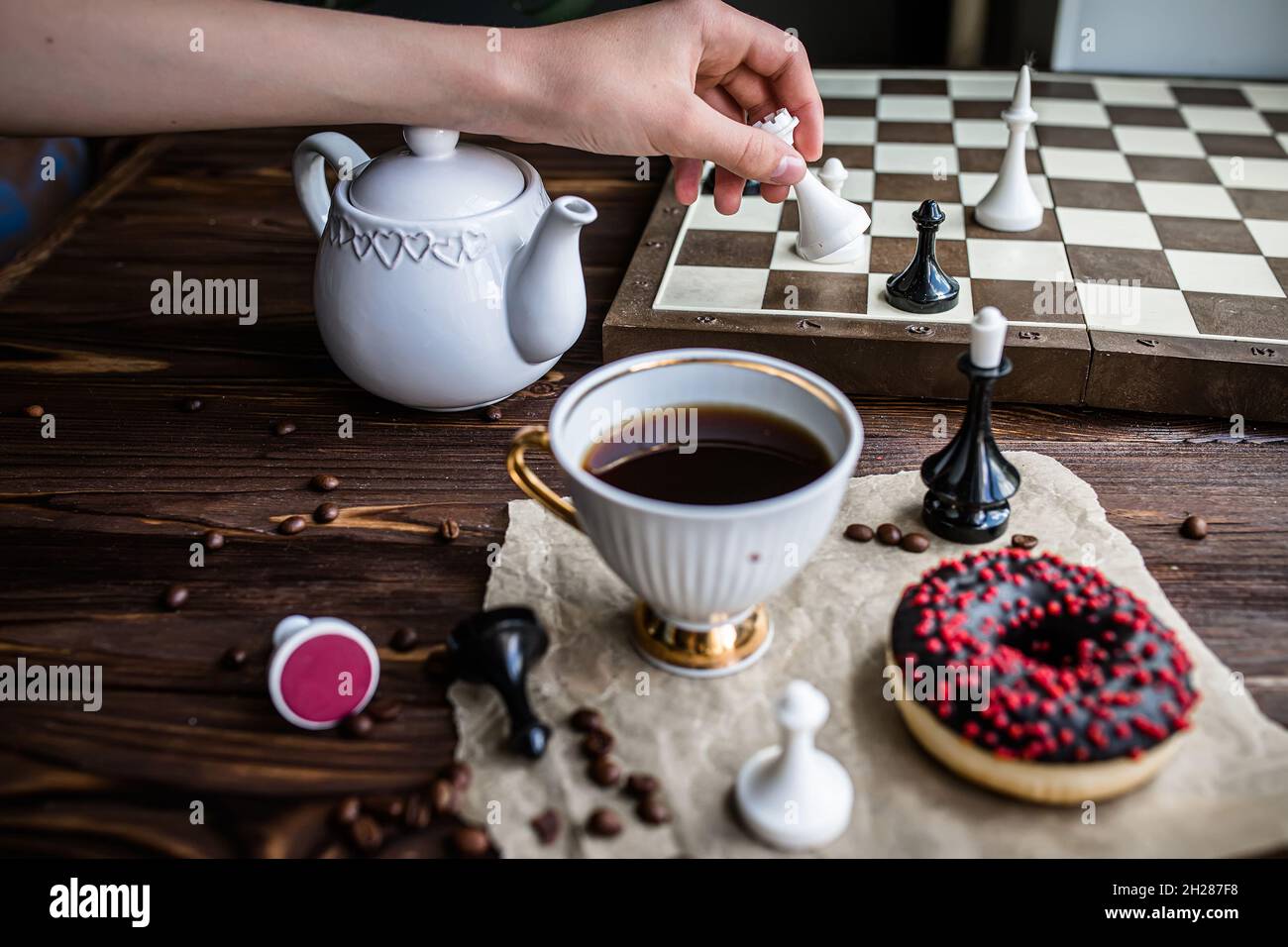 hand holds a white vintage chess piece. Chess board and scattered chess ...
