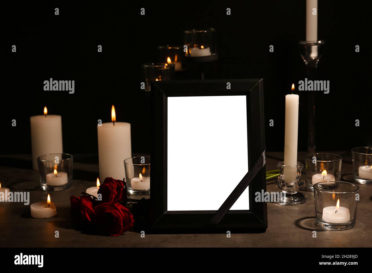 Empty frame with black ribbon, candles and roses on table. Funeral