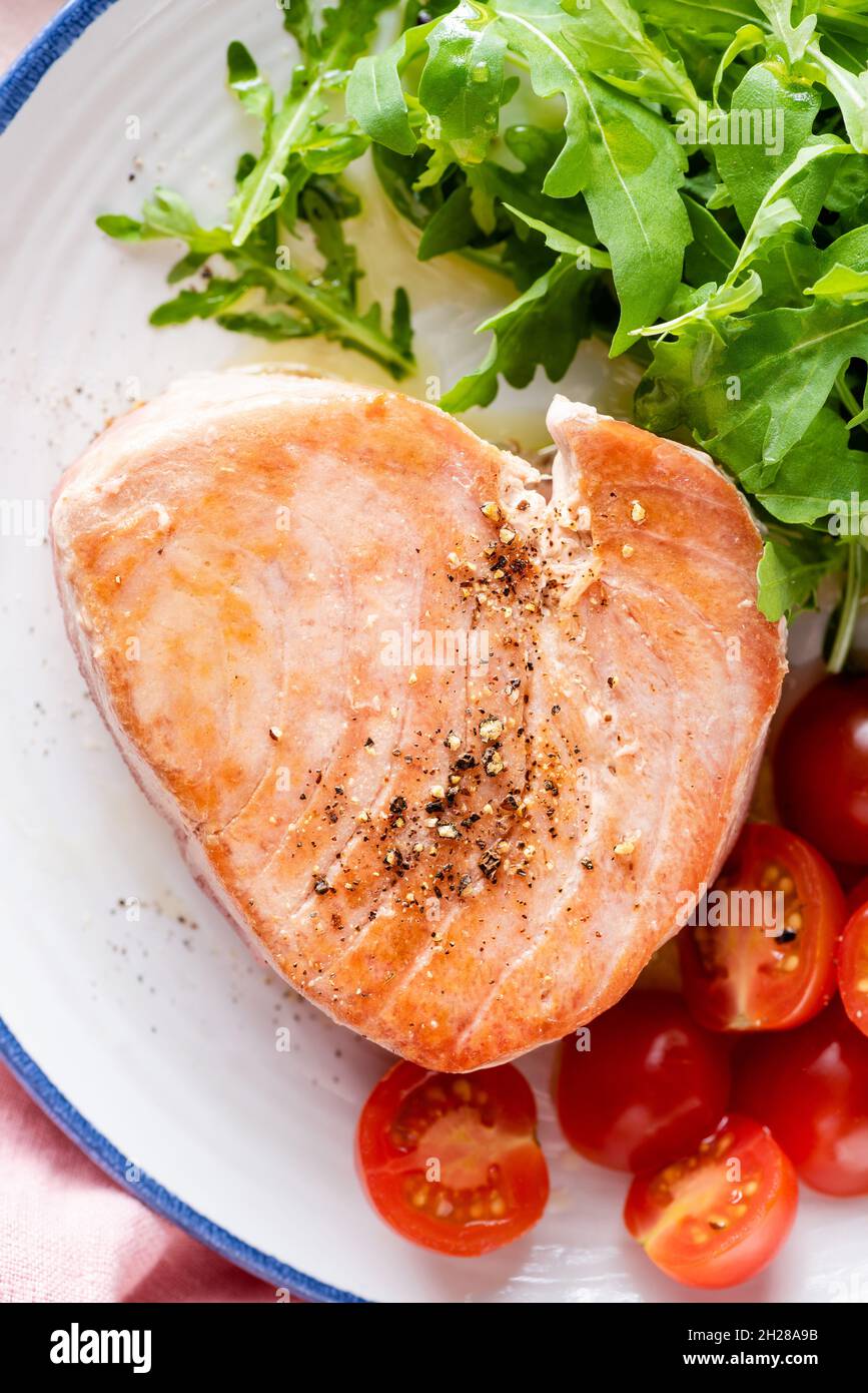 Pink tuna steak fried served with vegetables on a plate, top view