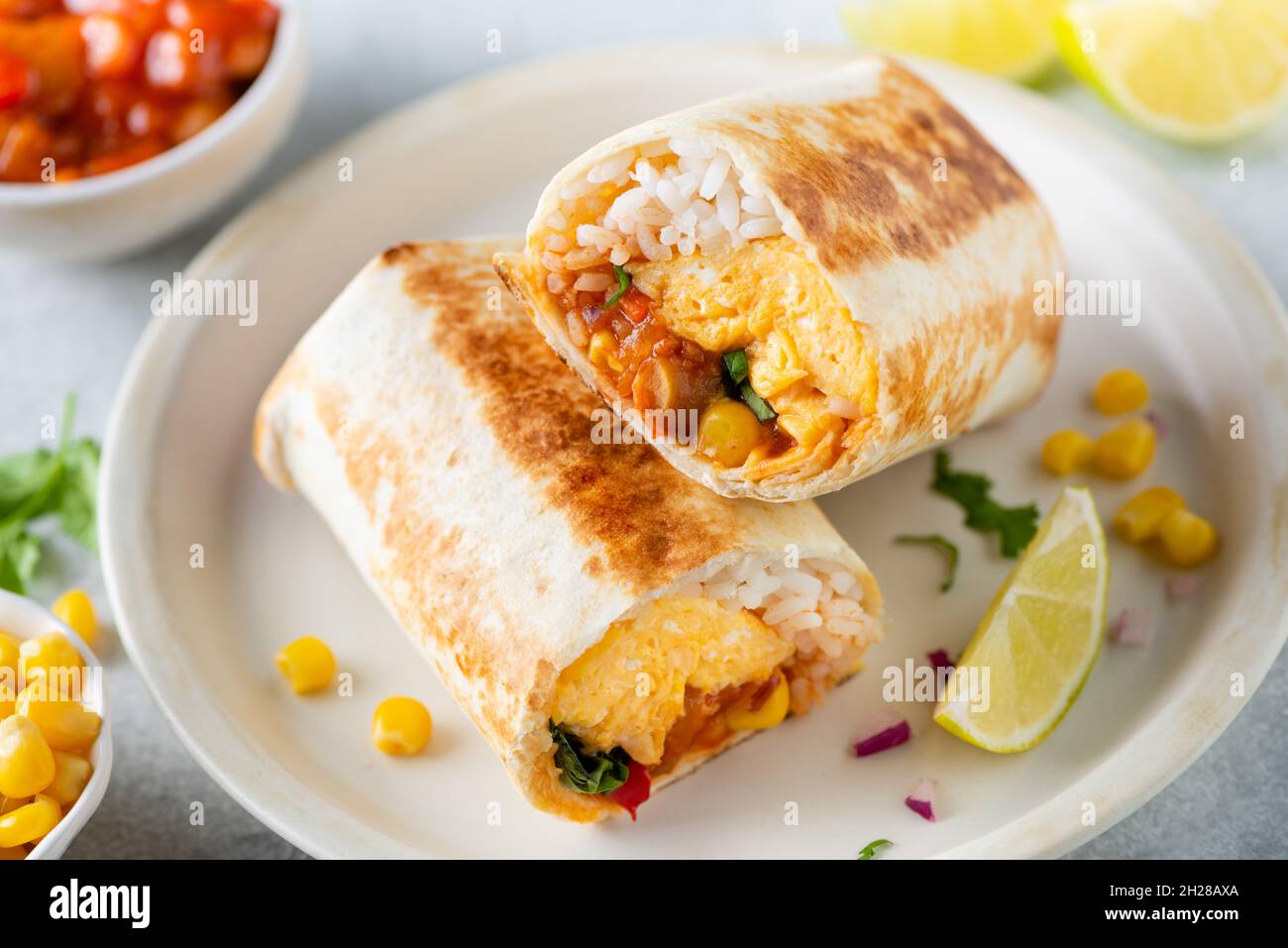 Breakfast tortilla wrap with omelette and vegetables on a plate. Healthy vegetarian burrito with eggs Stock Photo