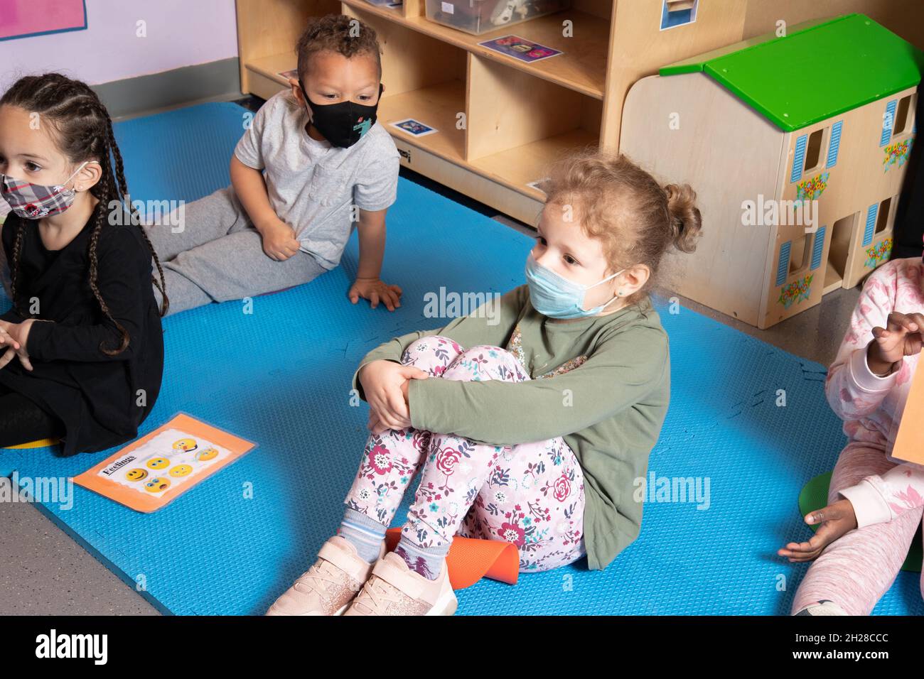 Education Preschool 3-4 year olds morning meeting small gropu of children listening, all wearing face masks to protect against Covid-19 infection Stock Photo