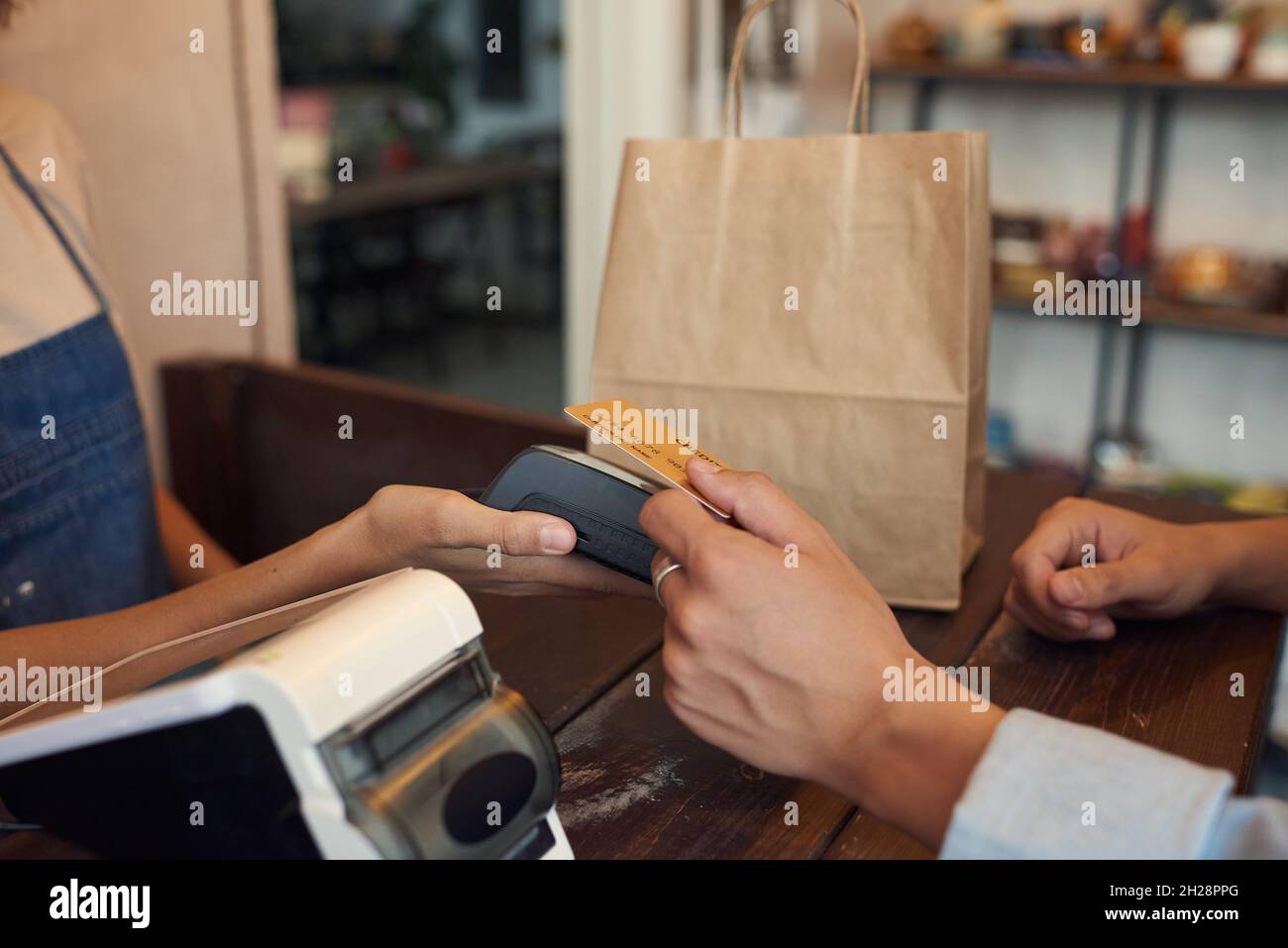 Close-up of unrecognizable customer paying with wireless card and ...