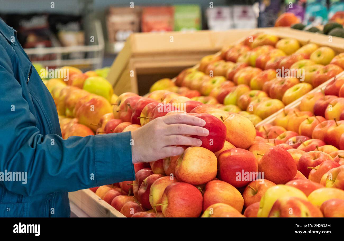 https://c8.alamy.com/comp/2H2938M/choosing-organic-apple-in-the-market-woman-selecting-fresh-red-apples-in-grocery-store-female-hand-taking-fruit-from-a-shelf-street-view-travel-2H2938M.jpg