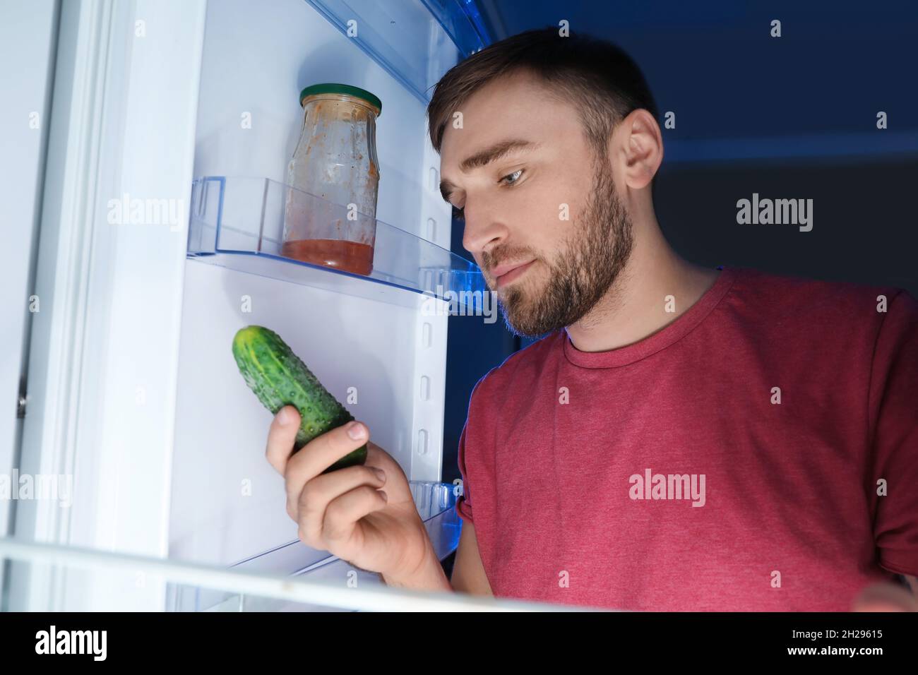 Man taking fresh cucumber out of refrigerator Stock Photo Alamy