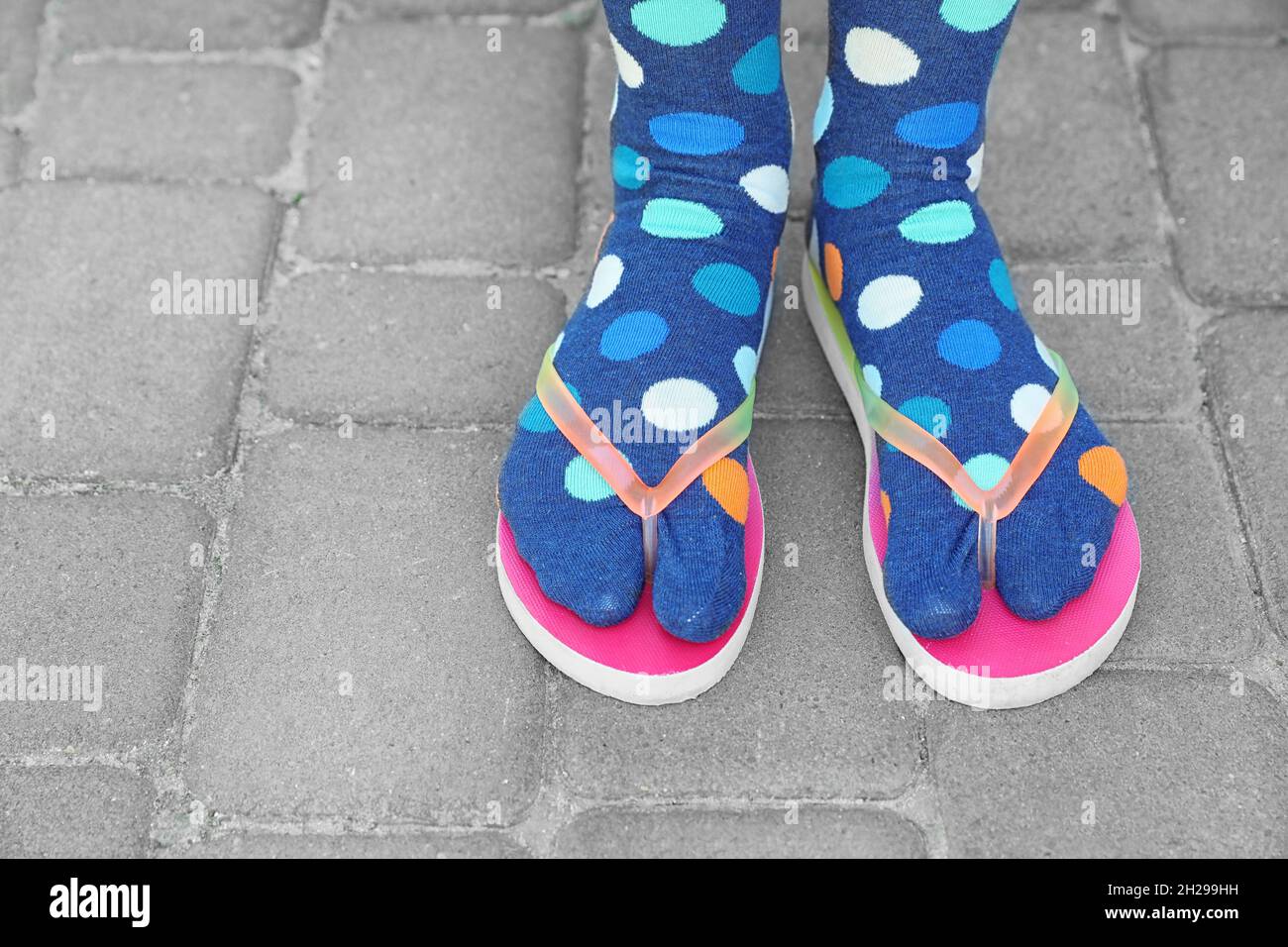 Woman wearing bright socks with flipflops standing outdoors Stock