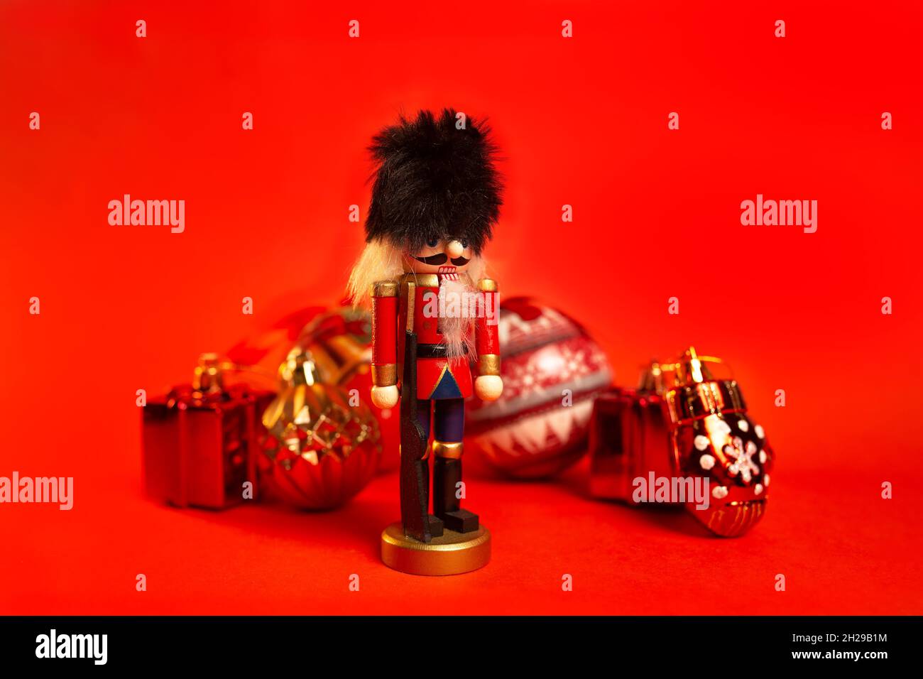 christmas nutcracker figurine with decorations on a red background. Stock Photo
