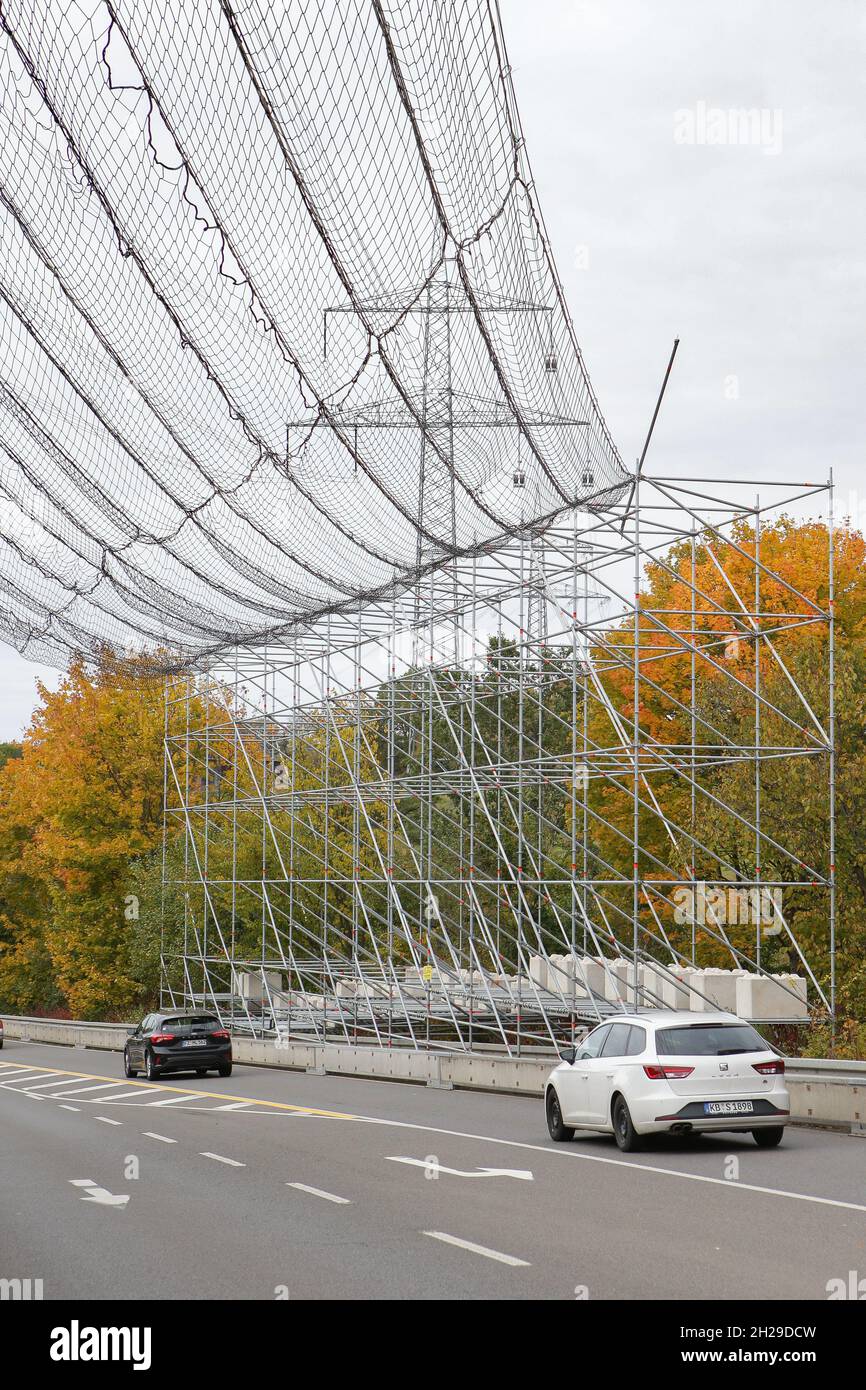 A large scaffolding with safety net to protect the road traffic due to work on a high-voltage line and the power poles. Stock Photo