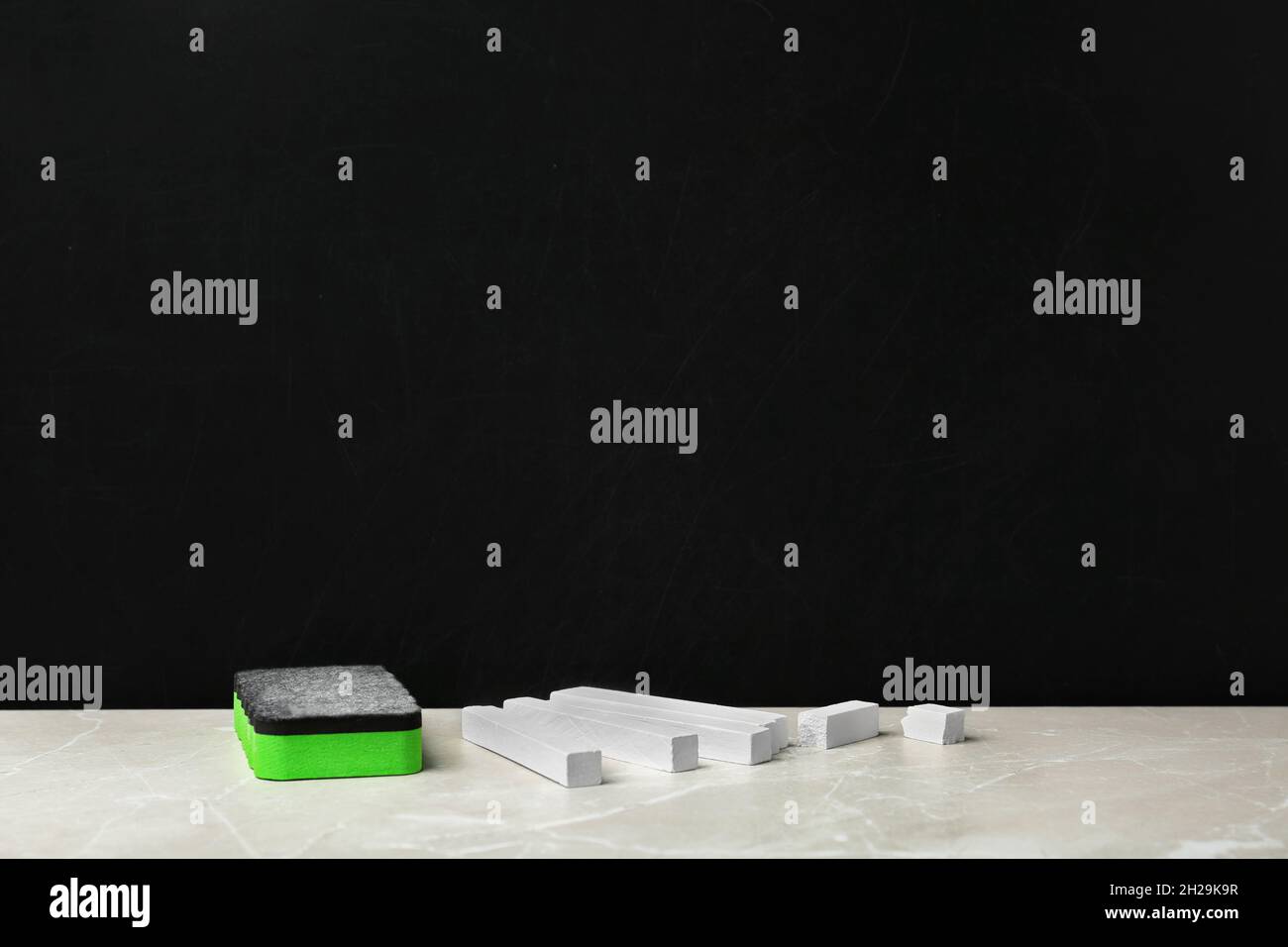 Pieces of chalk and duster on table near blackboard Stock Photo Alamy