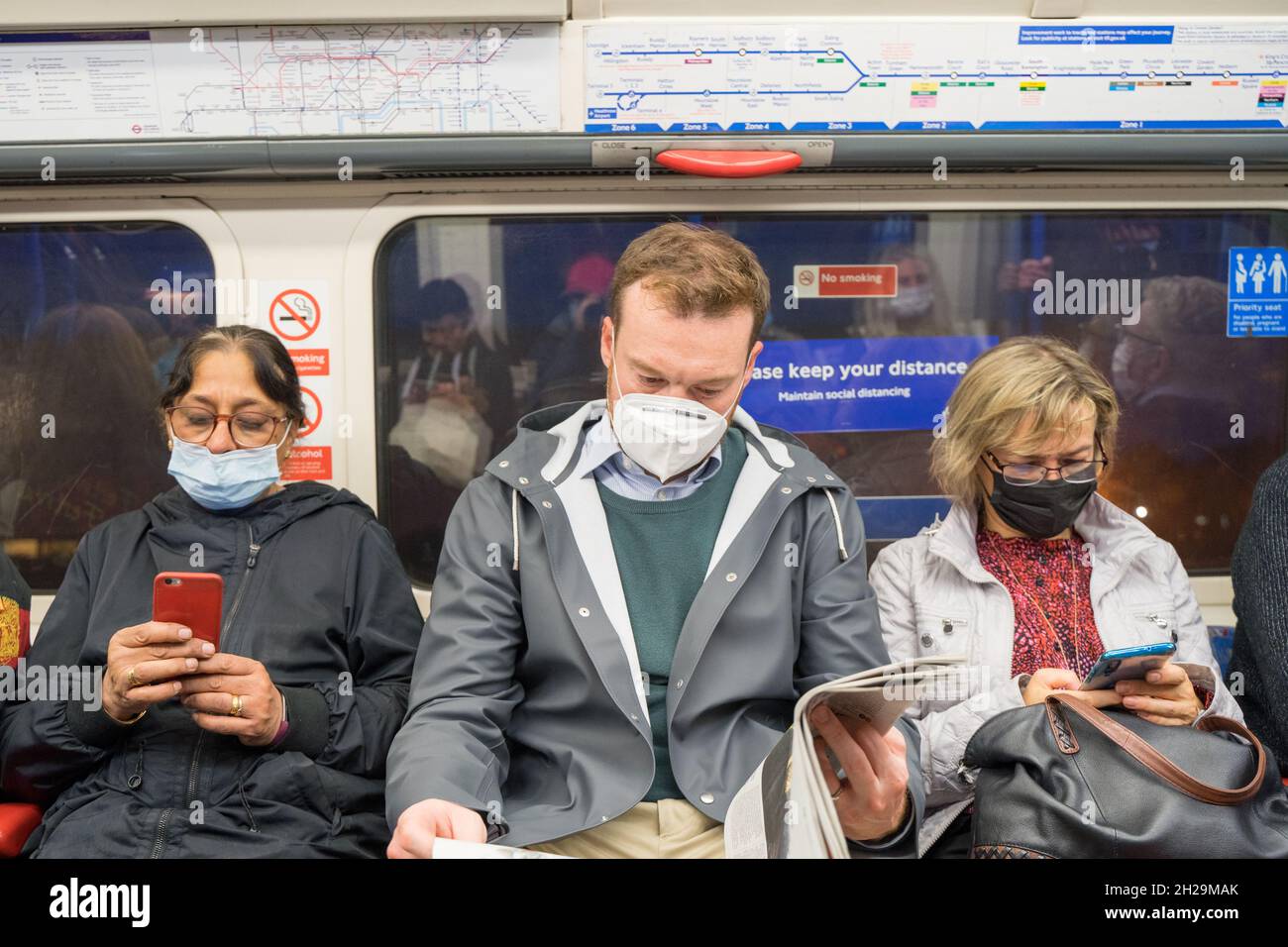 London Underground passengers sitting next each other wearing face