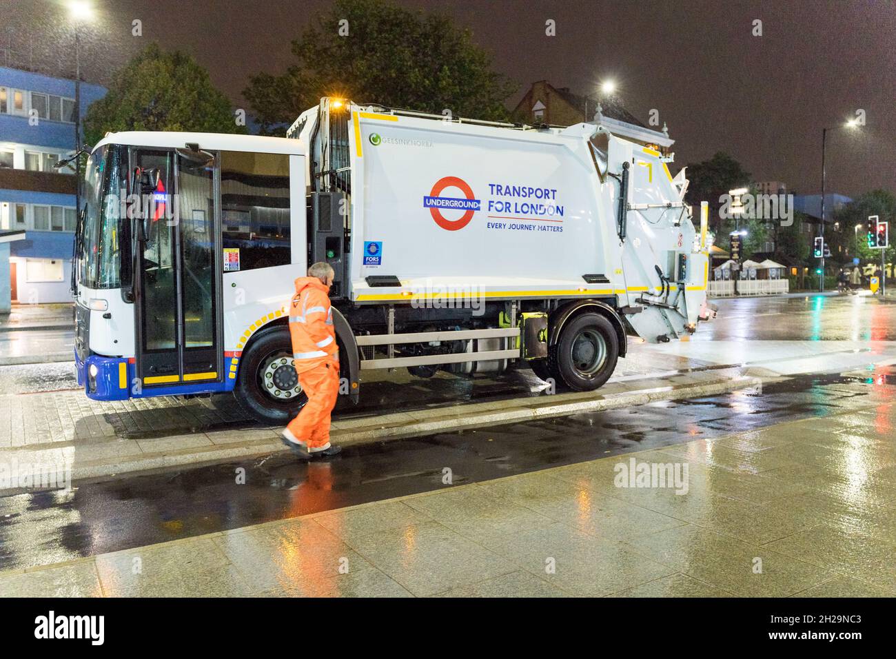 Waste management truck and driver working at night for London Transport network England UK Stock