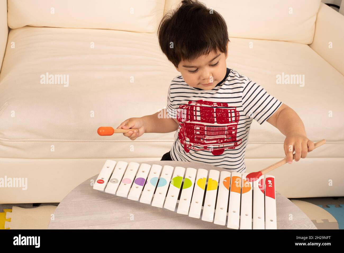 2 year old toddler boy playing wooden xylophone with mallets Stock Photo