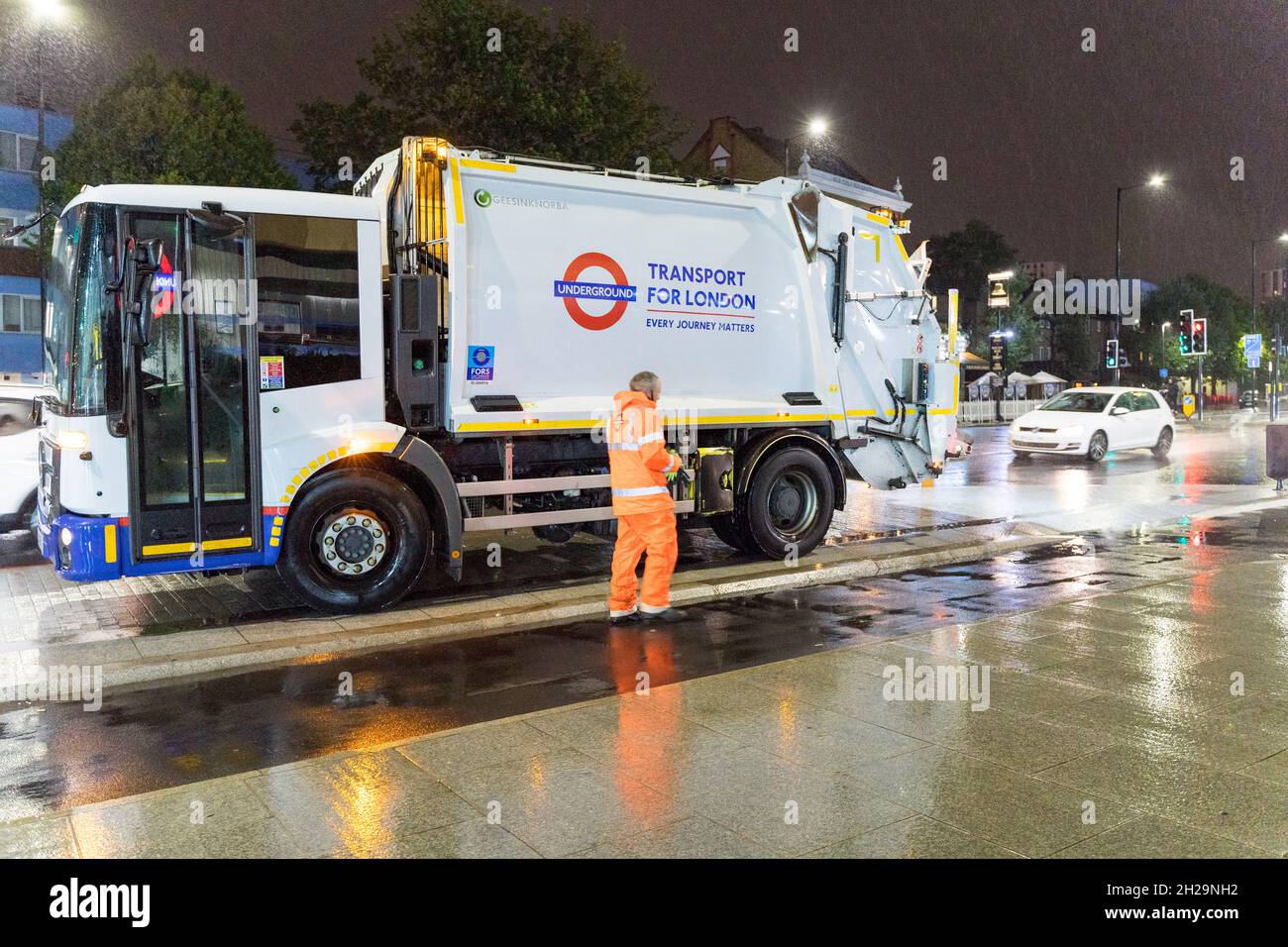 Waste management truck and driver working at night for London Transport network England UK Stock
