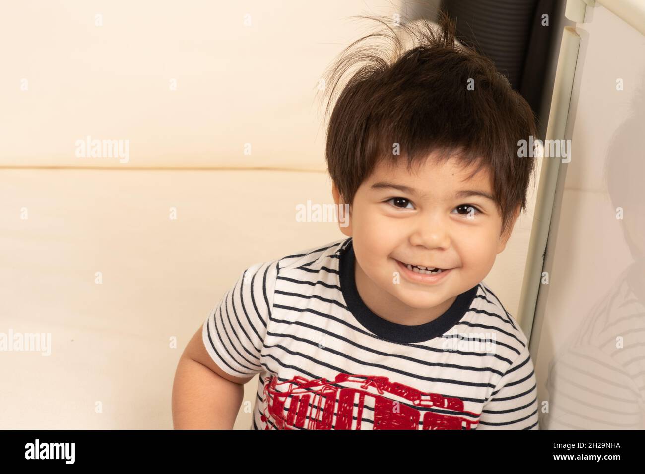 2 of 2 Two year old boy showing his face smiling after hiding behind his hands peek a boo Stock Photo