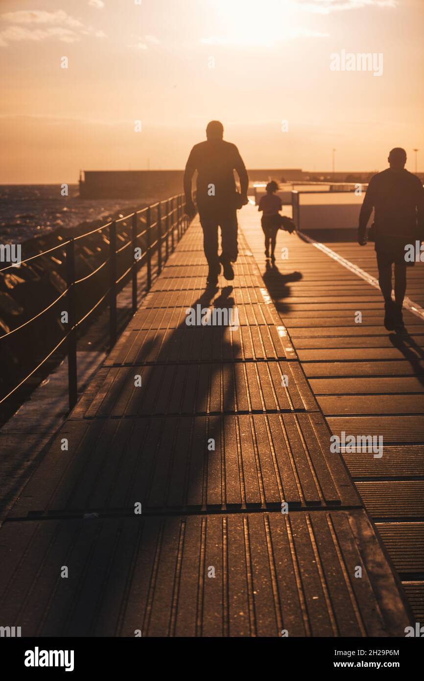 Silhouette of people walking along the promenade in the evening Stock ...