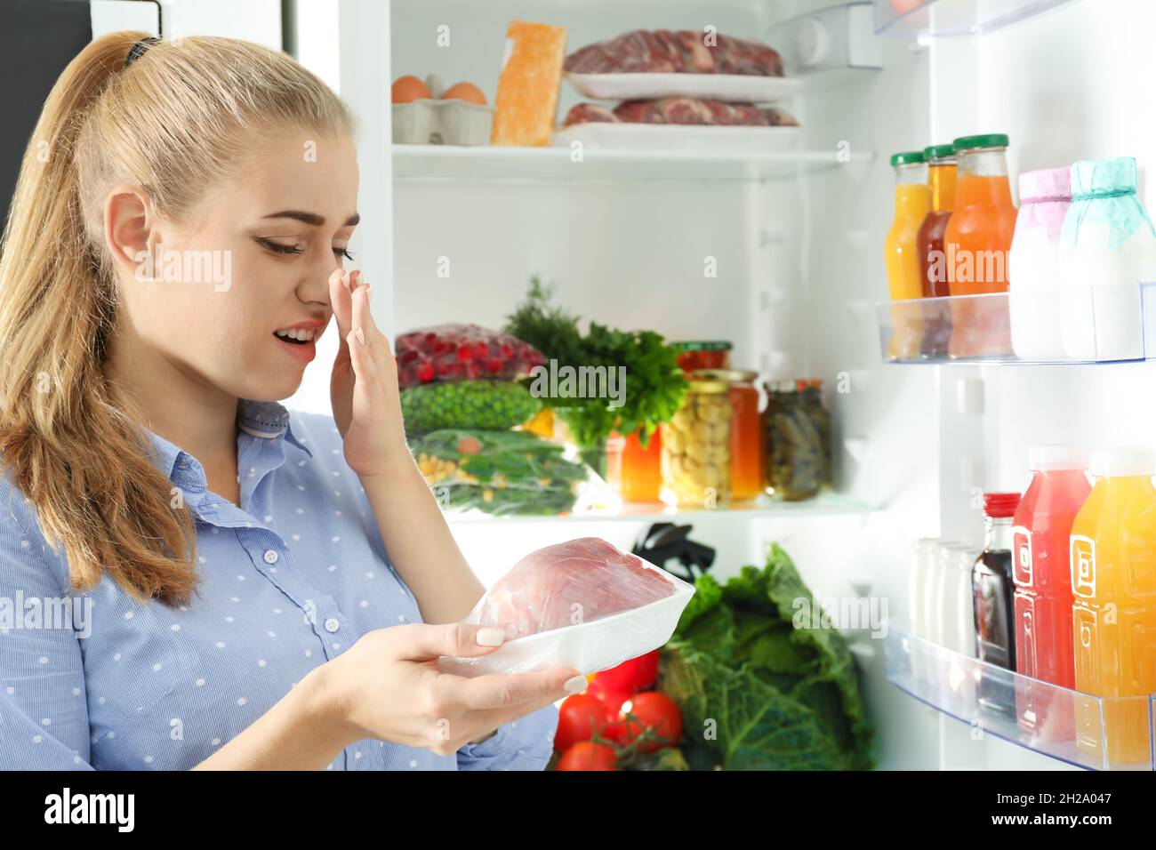 Woman taking stale meat out of refrigerator in kitchen Stock Photo Alamy