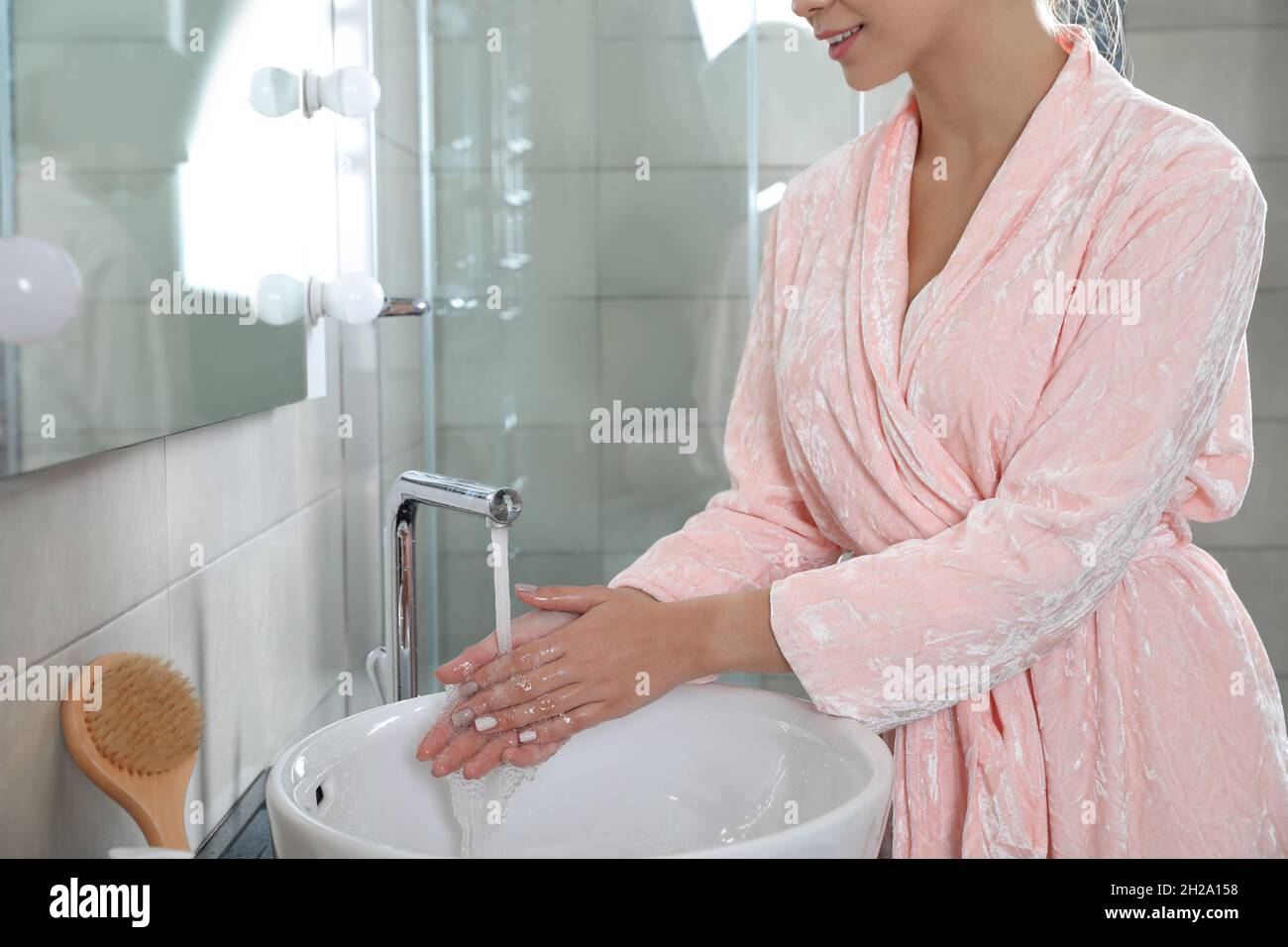 Young woman washing hands in bathroom. Using soap Stock Photo - Alamy