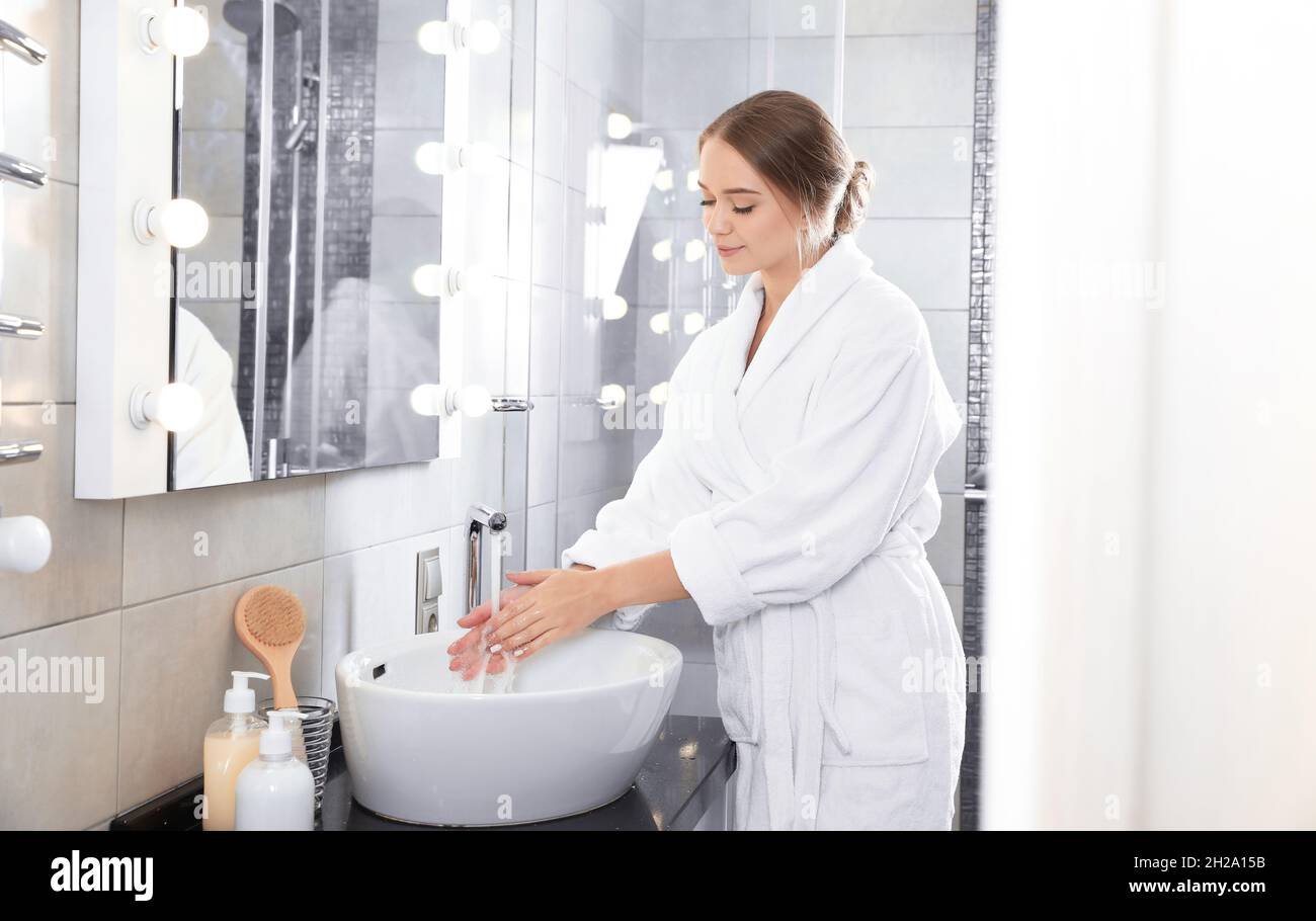Young woman washing hands in bathroom. Using soap Stock Photo - Alamy