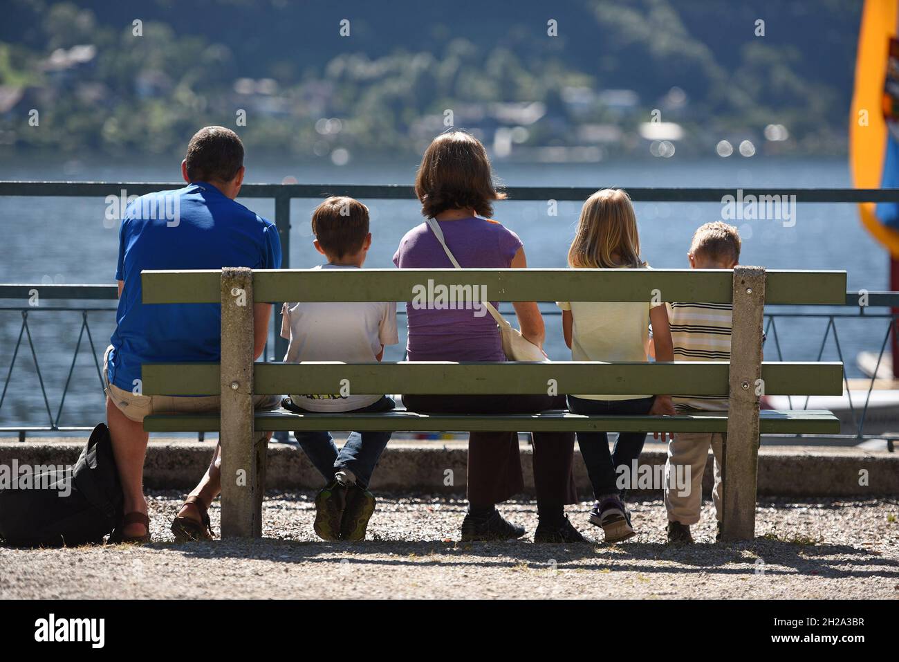 Familie genießt auf einer Bank an der Esplanade in Gmunden im Sommer die Sonne - Family enjoys the sun on a bench on the Esplanade in Gmunden in summe Stock Photo