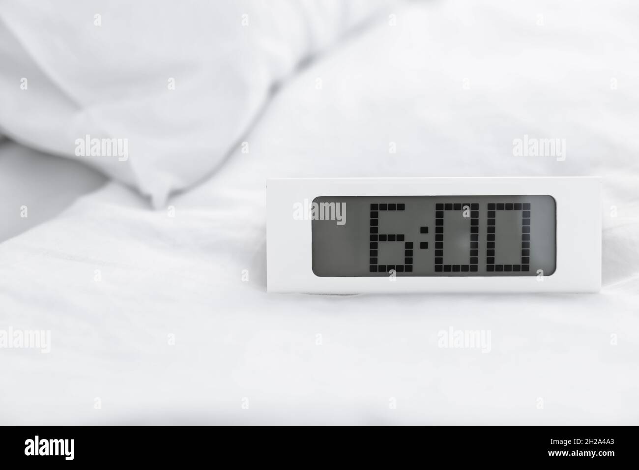 Digital alarm clock on bed. Time to wake up Stock Photo