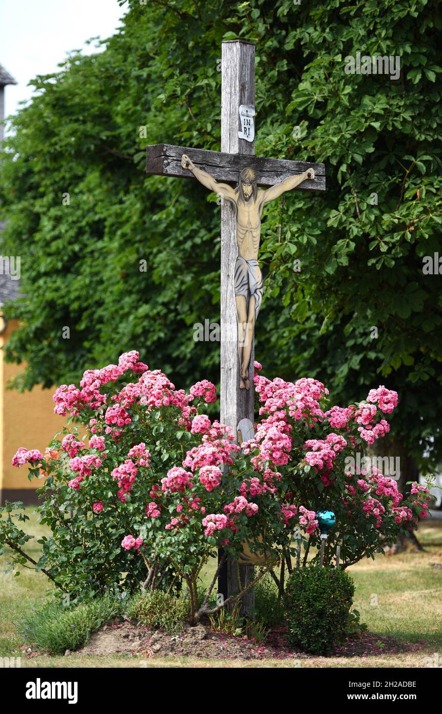 Ein Wegkreuz an einer Straße mit Rosenstrauch im Salzkammergut, Österreich, Europa - A wayside cross on a street with rose bushes in the Salzkammergut Stock Photo