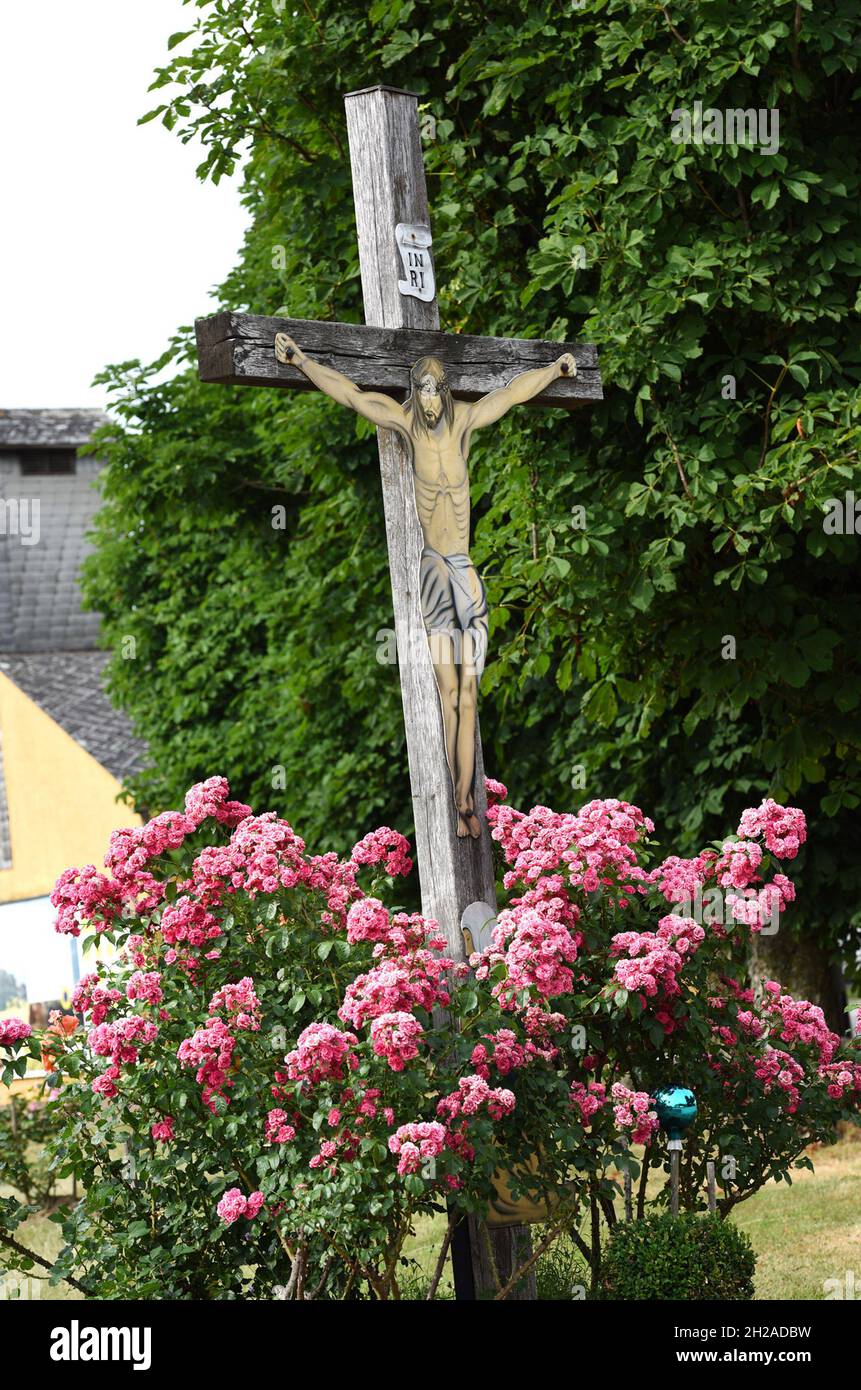 Ein Wegkreuz an einer Straße mit Rosenstrauch im Salzkammergut, Österreich, Europa - A wayside cross on a street with rose bushes in the Salzkammergut Stock Photo