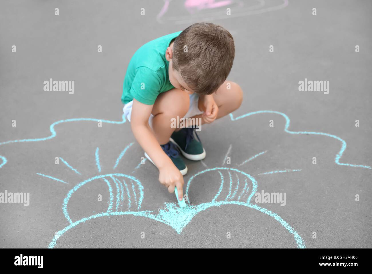 Little child drawing with chalk on asphalt Stock Photo - Alamy