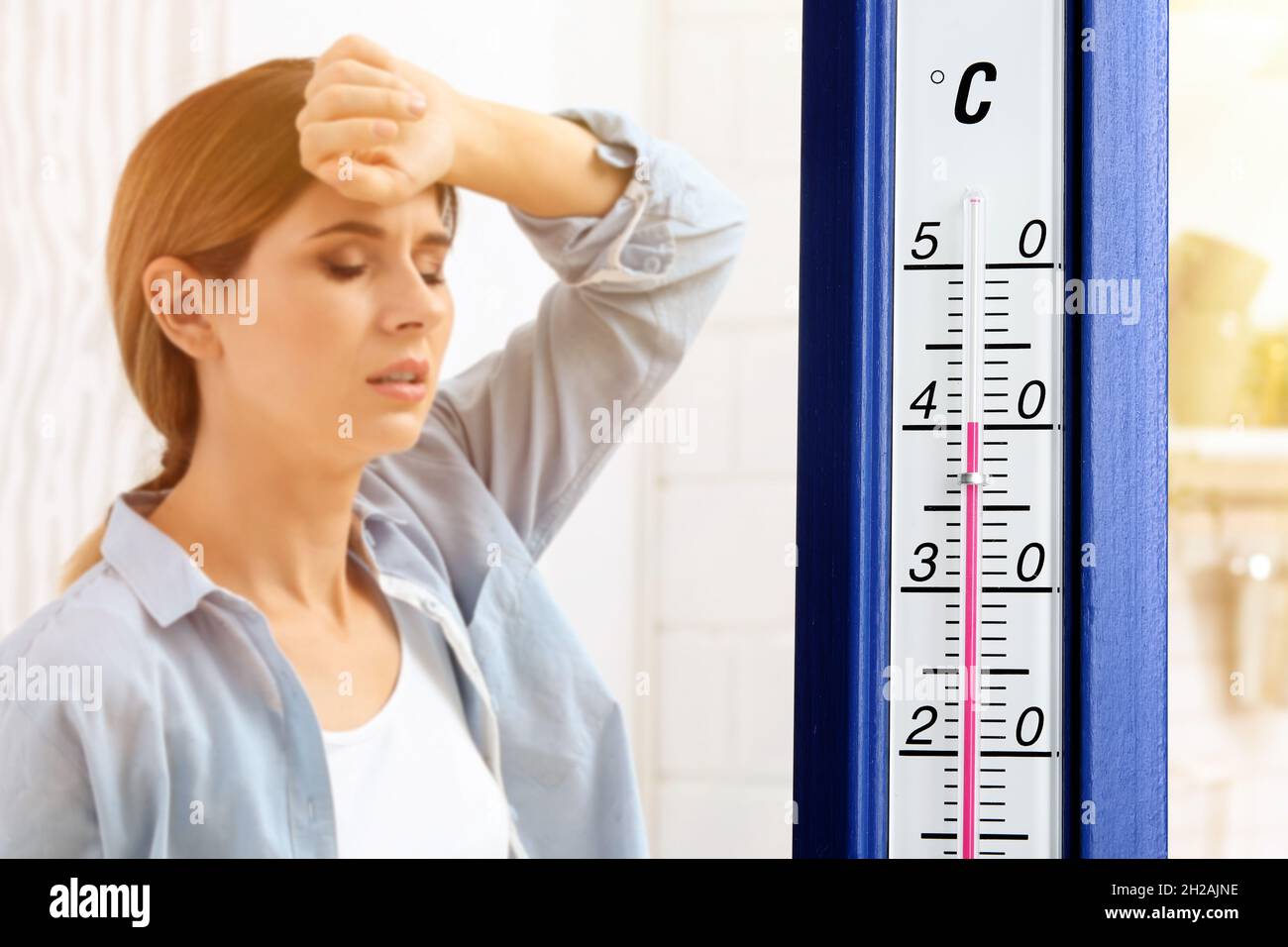 Extreme high temperature on thermometer and woman suffering from heat