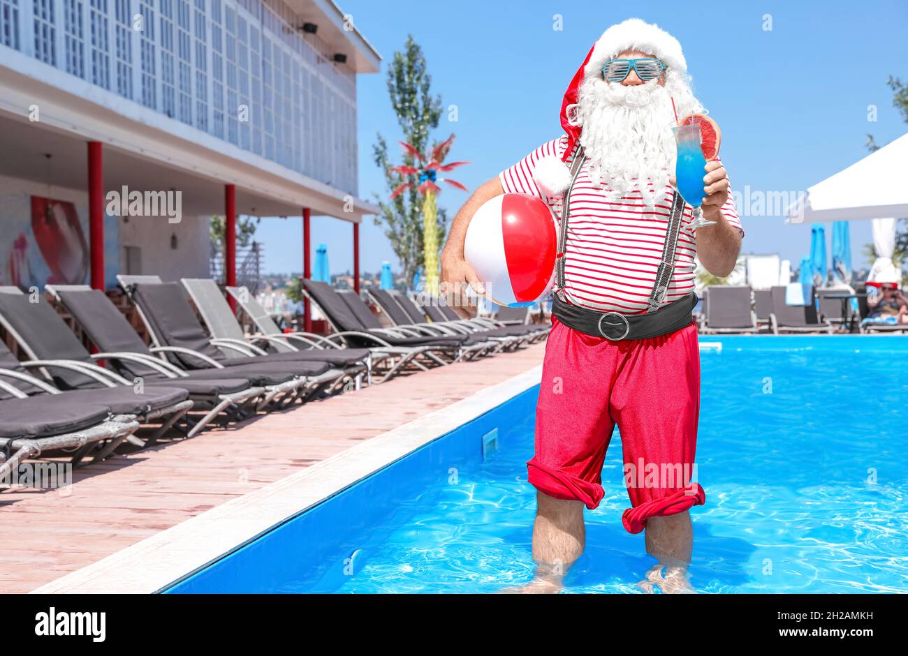 Authentic Santa Claus with cocktail and beach ball in pool at resort