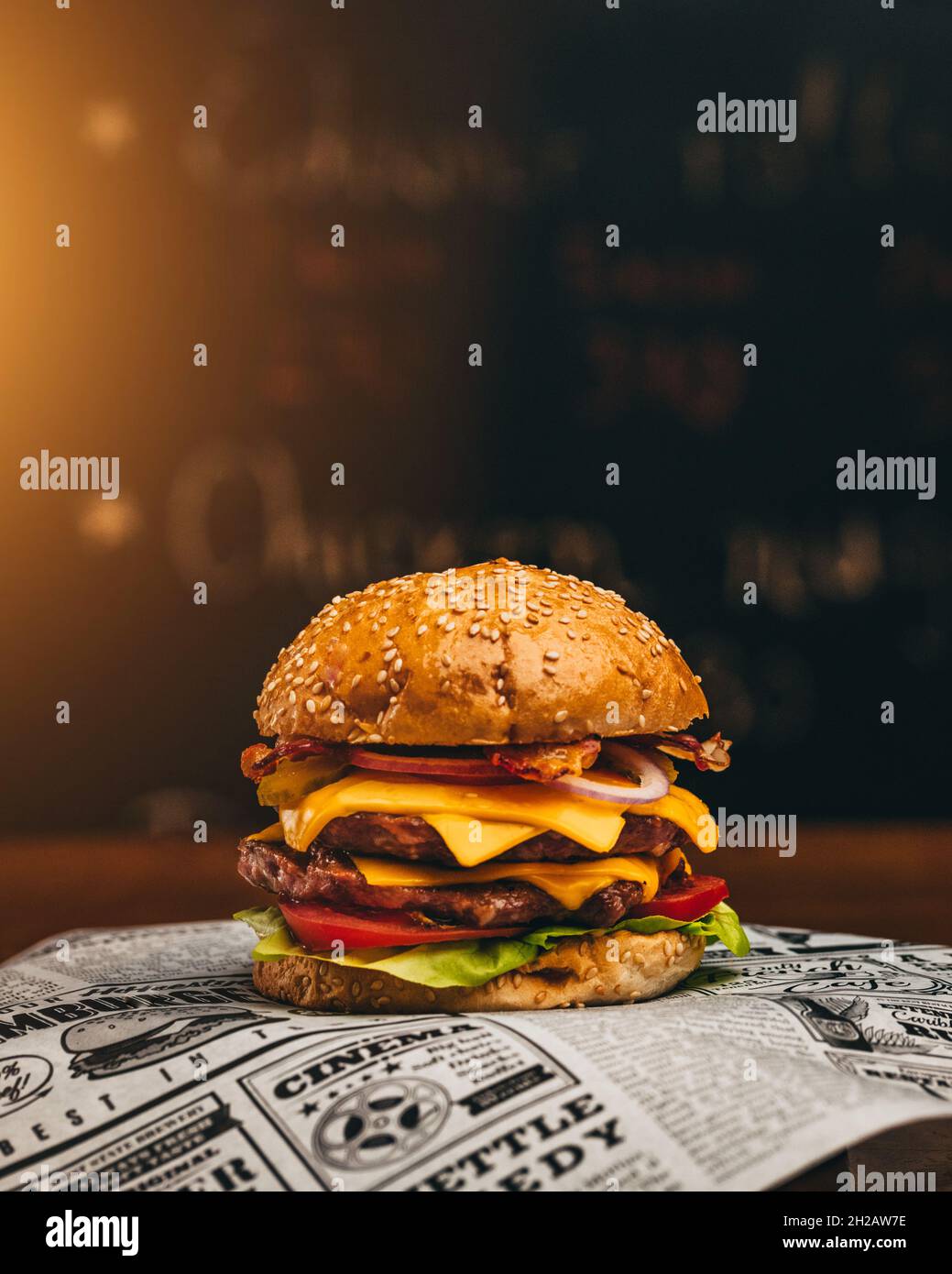 Delicious burger with lettuce, cheese, cucumbers, onion and tomato on dark background CLOSE UP Stock Photo