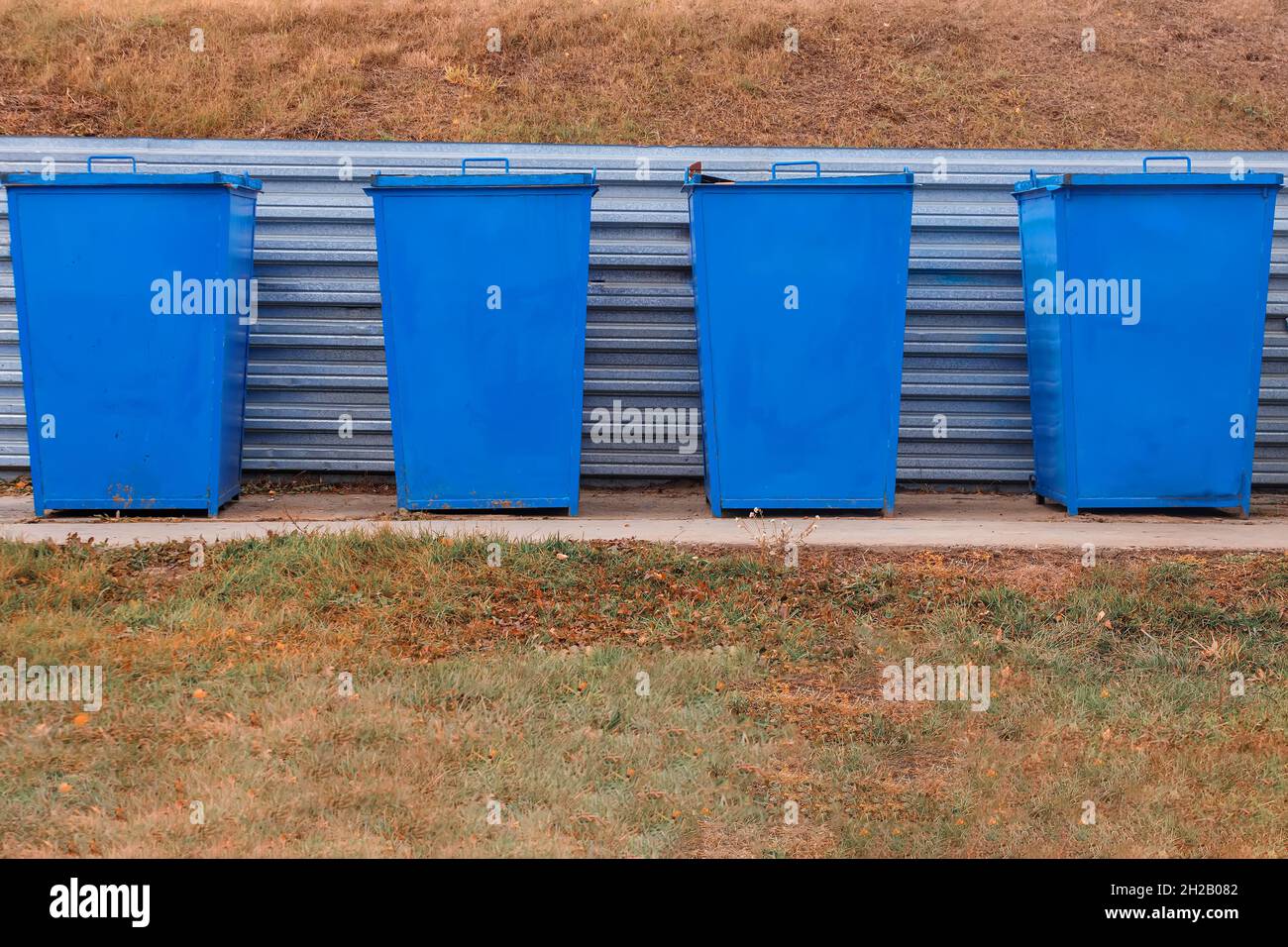 Metal garbage cans of blue color stand on a special area in the open